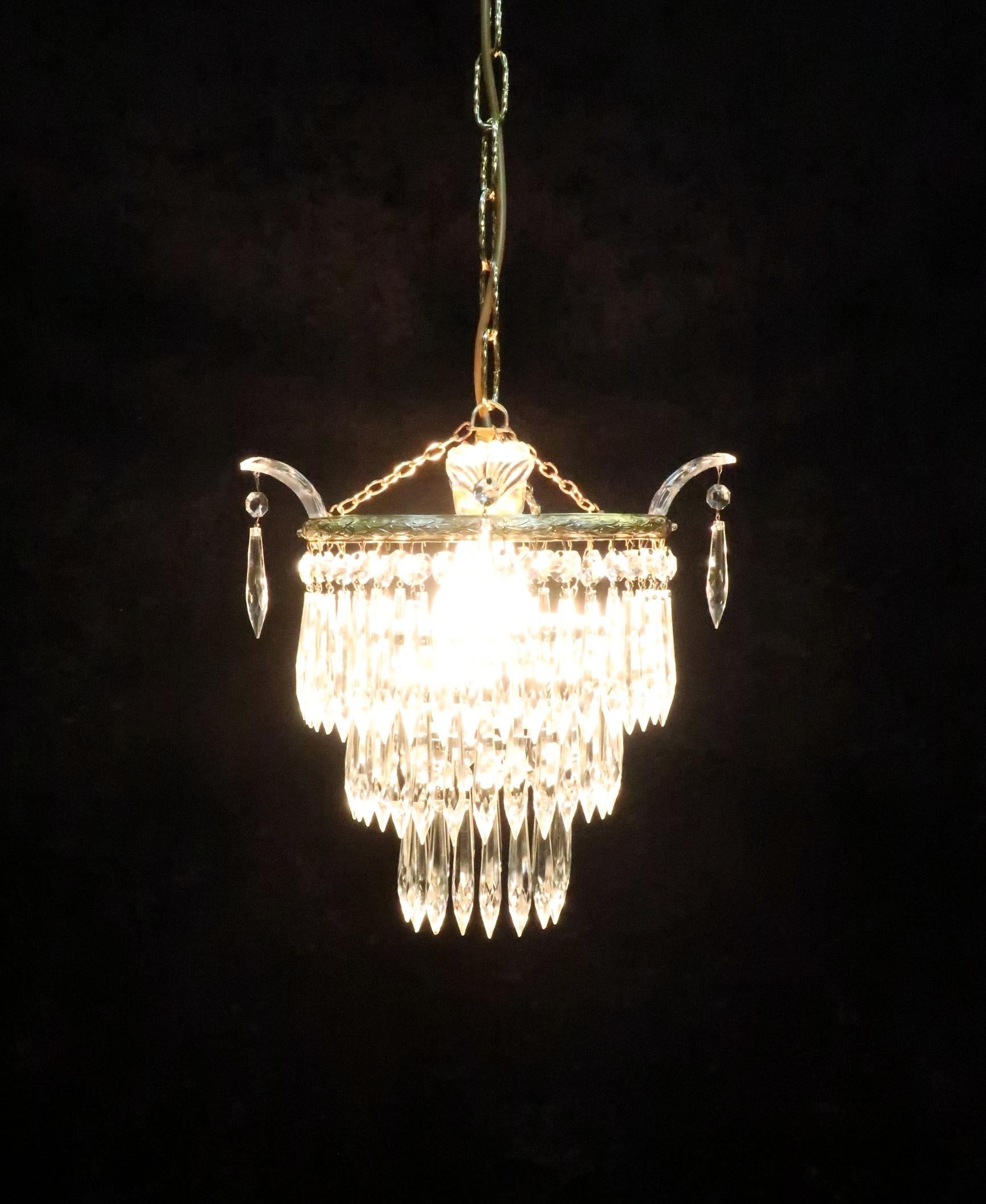 A very good quality ?Italian Art Deco chandelier with three tiers of crystal glass icicle droplets and crystal glass leaves to the top with decorative brass frame on an adjustable 12 inch chain. The brass has been cleaned and lacquered and the light