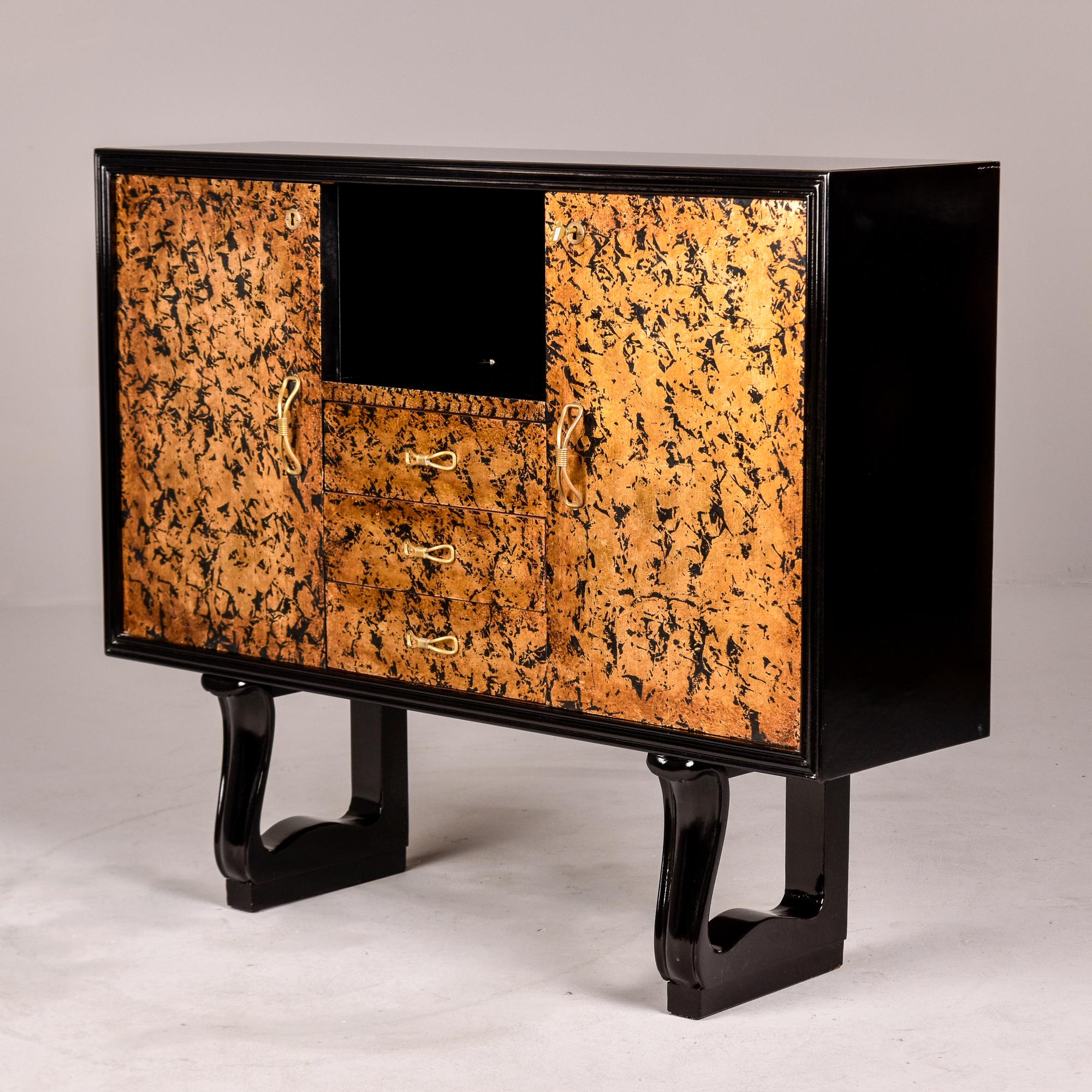 Found in Italy, this unusual Art Deco era cabinet dates from the 1940s. Top, sides and base of cabinet are ebonised and the front has a unique, foil-like gilt and ebony design. The cabinet features two locking side cabinets with hinged doors and a