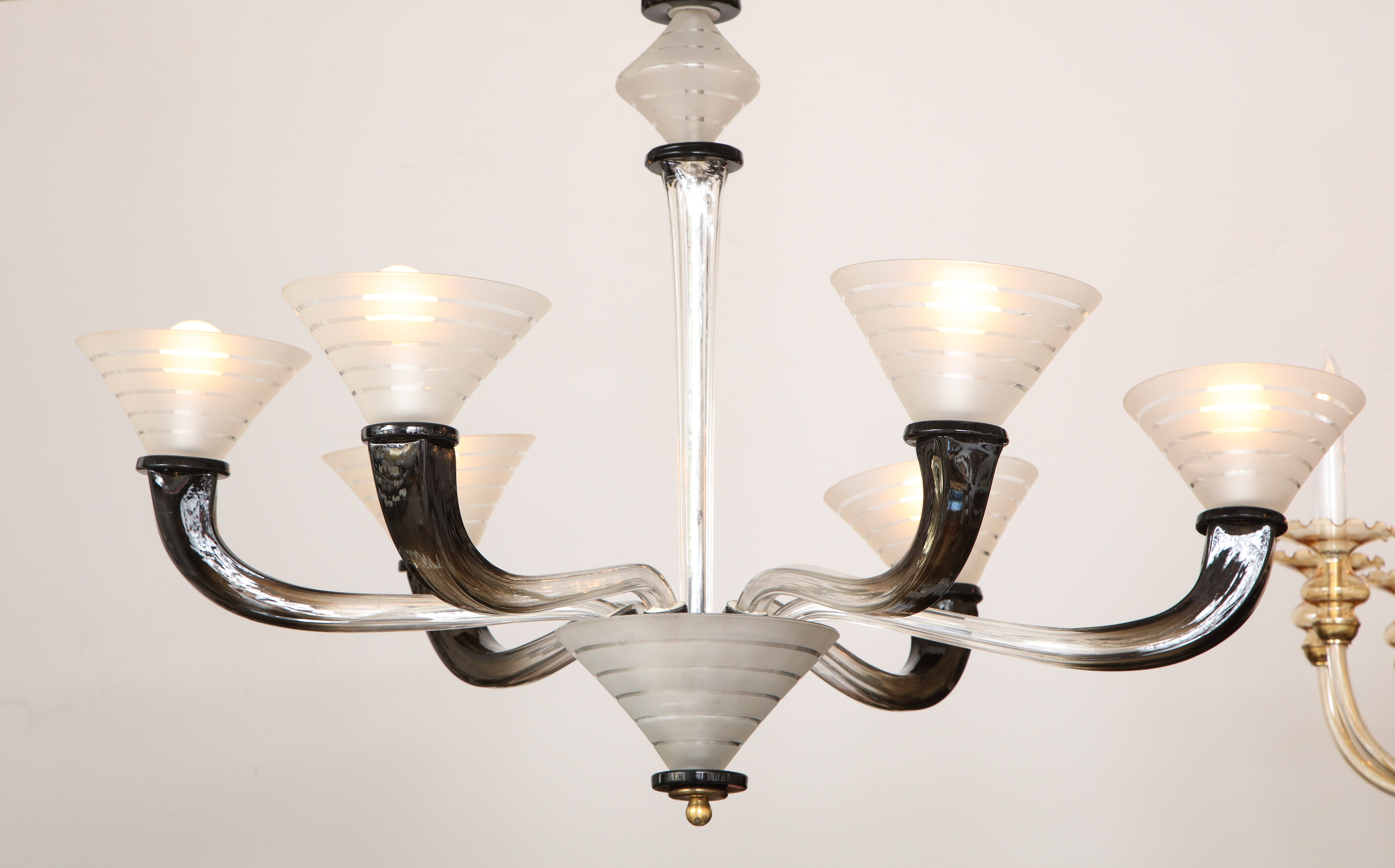 An Italian Art Deco six arm hand-blown glass Murano chandelier; the elegantly extended black glass arms surmounted by frosted glass lined bobeche, the whole supported by a central columnar stem support with the frosted glass motif echoed in the