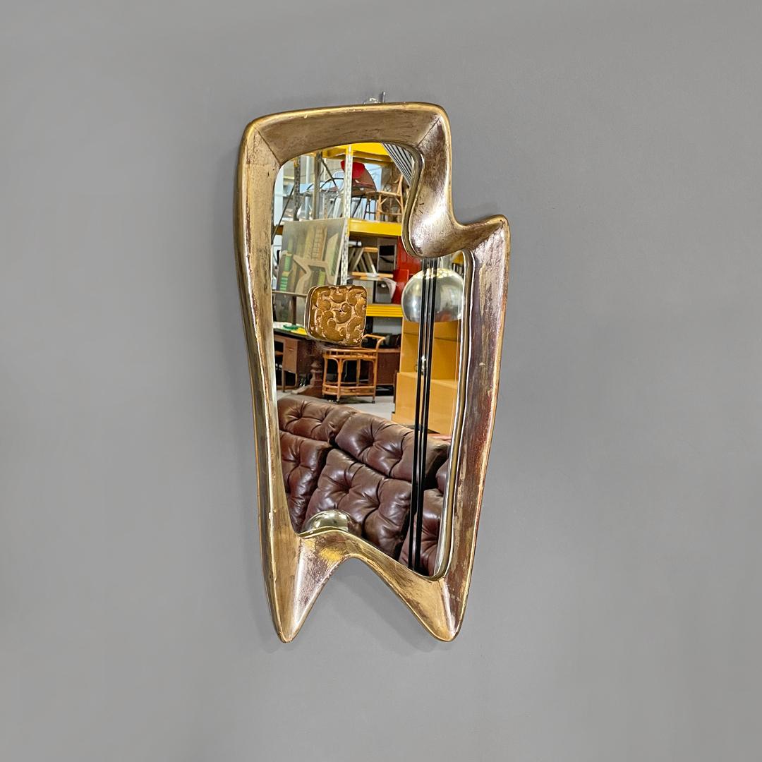 Italian Art Deco golden wood wall mirror with abstract curved structure, 1940s
Wall mirror with golden and silver wooden frame. The structure has an abstract, curved and rounded elongated shape, with raised edges. On the mirror there is a square