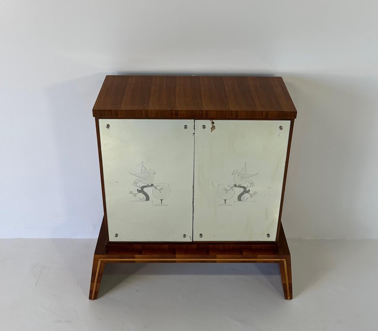 This Art Deco Bar Cabinet was produced in Italy in the 1940s and is attributed to a design by Osvaldo Borsani. 
The top, the base and the laterals are in walnut, the detail on the base is a profile in maple, while the doors are two original mirrors