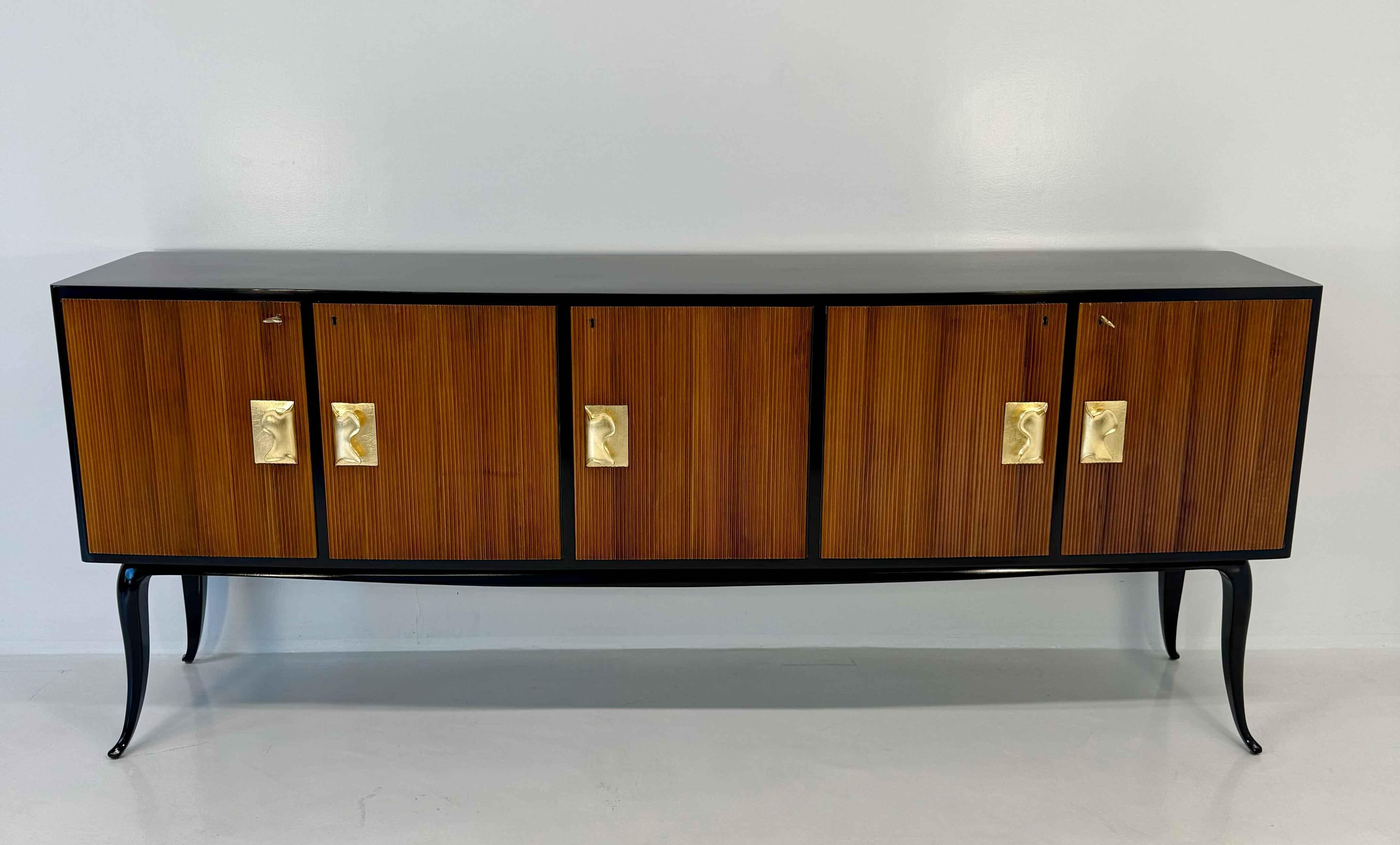 Elegante credenza italiana degli anni '50, attribuita a Osvaldo Borsani. La struttura è completamente rifinita in lacca nera lucida, con ante scanalate in noce che aggiungono ritmo e profondità al design complessivo. Le maniglie finemente