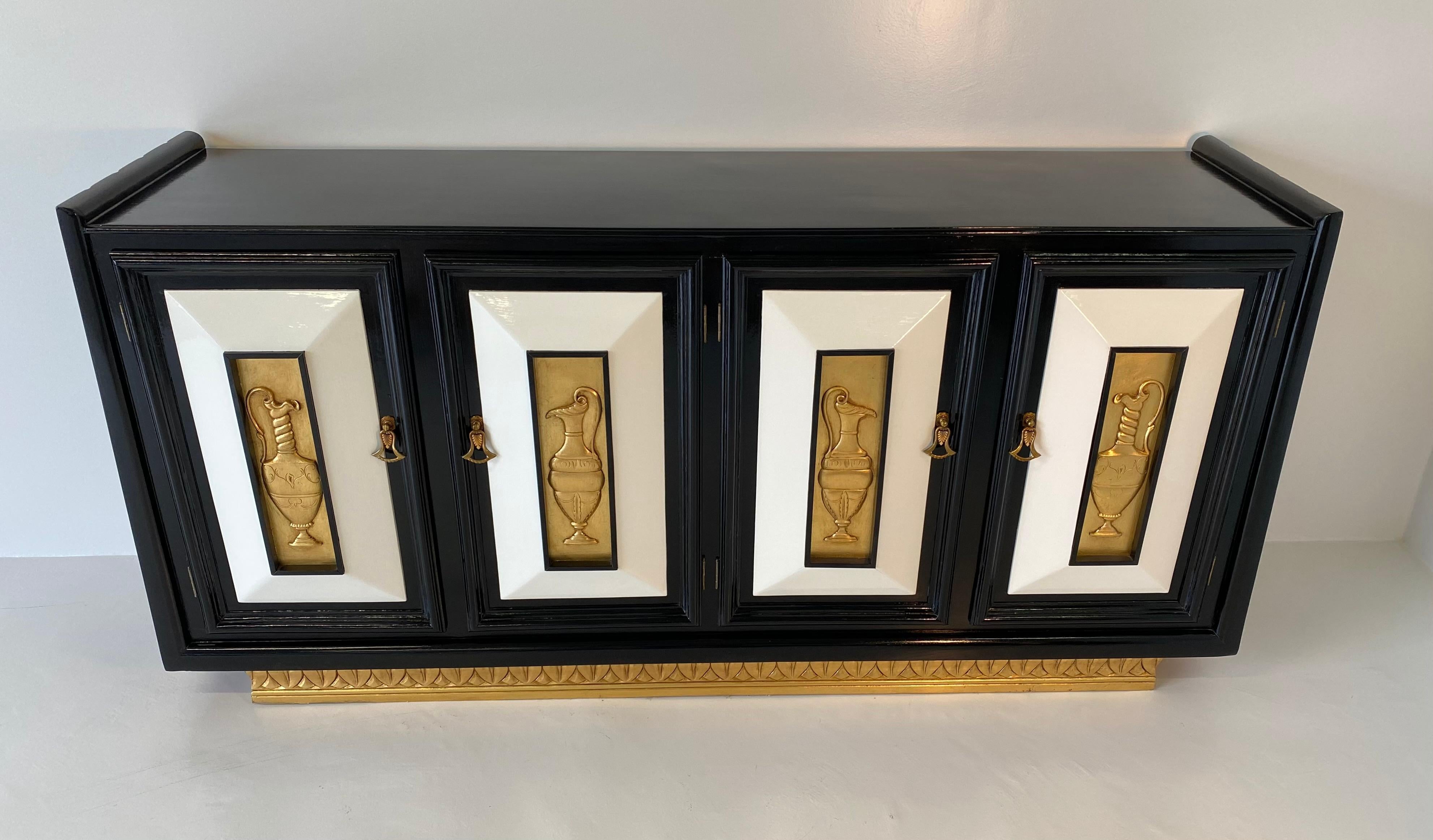 1940s Art Deco sideboard in ebonized oakwood with ivory lacquered details and gold-leafed solid wood engravings, the handles are made of brass and Bakelite.
On the inside of the four doors there are some shelves.
Completely restored.
 