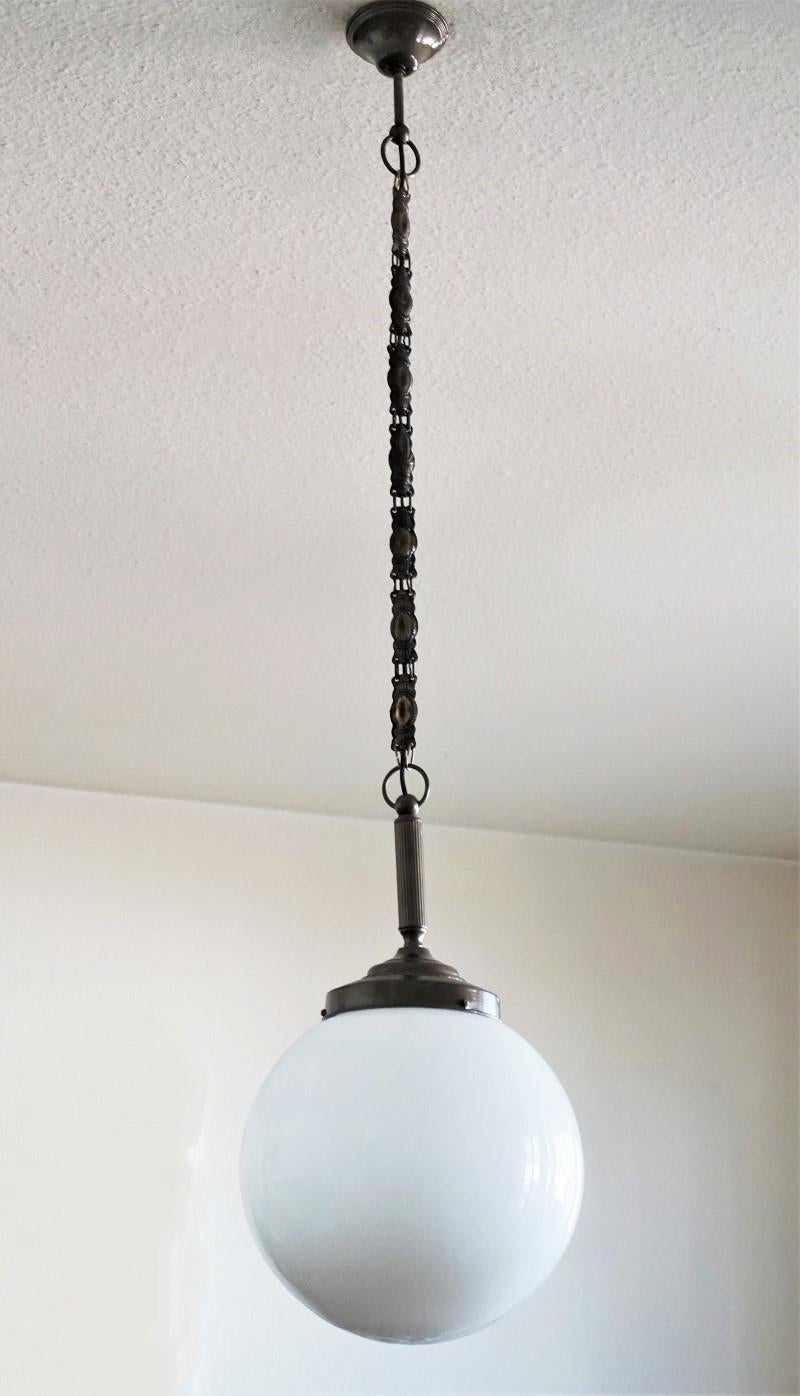 A large Italian ball hand blown opaline glass ball pendant with burnished brass mounts, chain and canopy, circa 1930-1939.
One brass and porcelain Edison E27 light socket for a large sized light bulb up to 100W.
Measures: Diameter 13.75