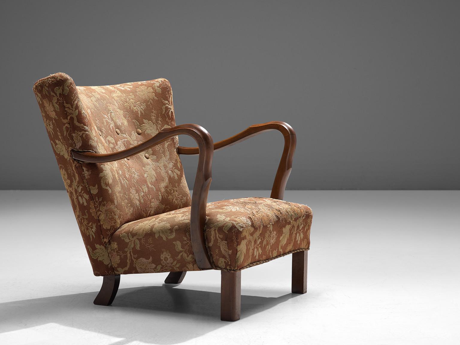 Lounge chair, wood and floral upholstery, Italy, 1930s.
 
Italian armchairs in Art Deco style of the 1930s. The most distinctive feature of this easy chairs are the armrests elegantly curved around the seating. The warm color of the wood armrests