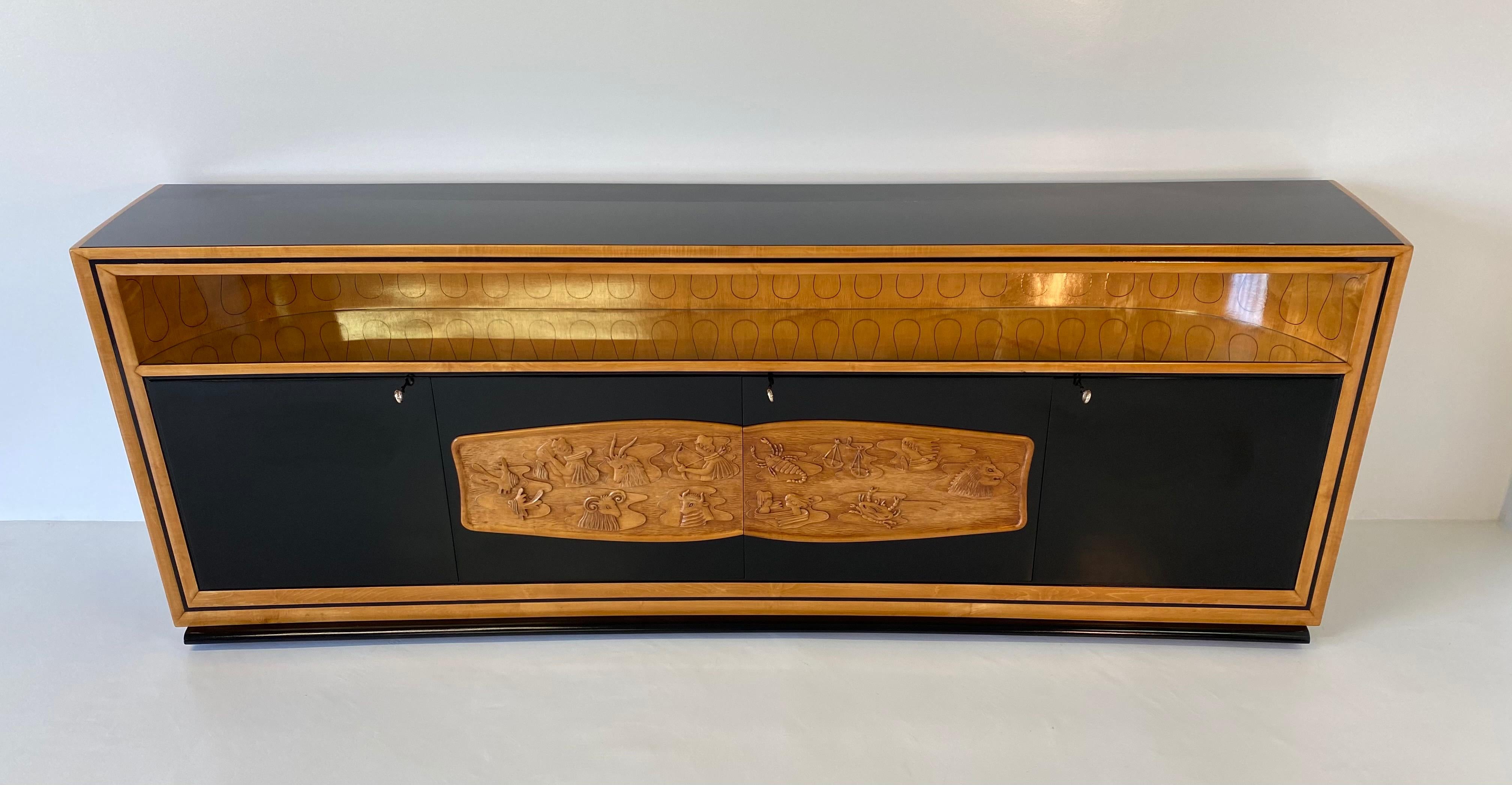 This item was produced in the 1940s in Cantù ( Italy ) by Vittorio Dassi for the ' Permanente Mobili Cantù'.
This precious sideboard is entirely black lacquered, the profiles and the large central decoration are in carved maple representing the