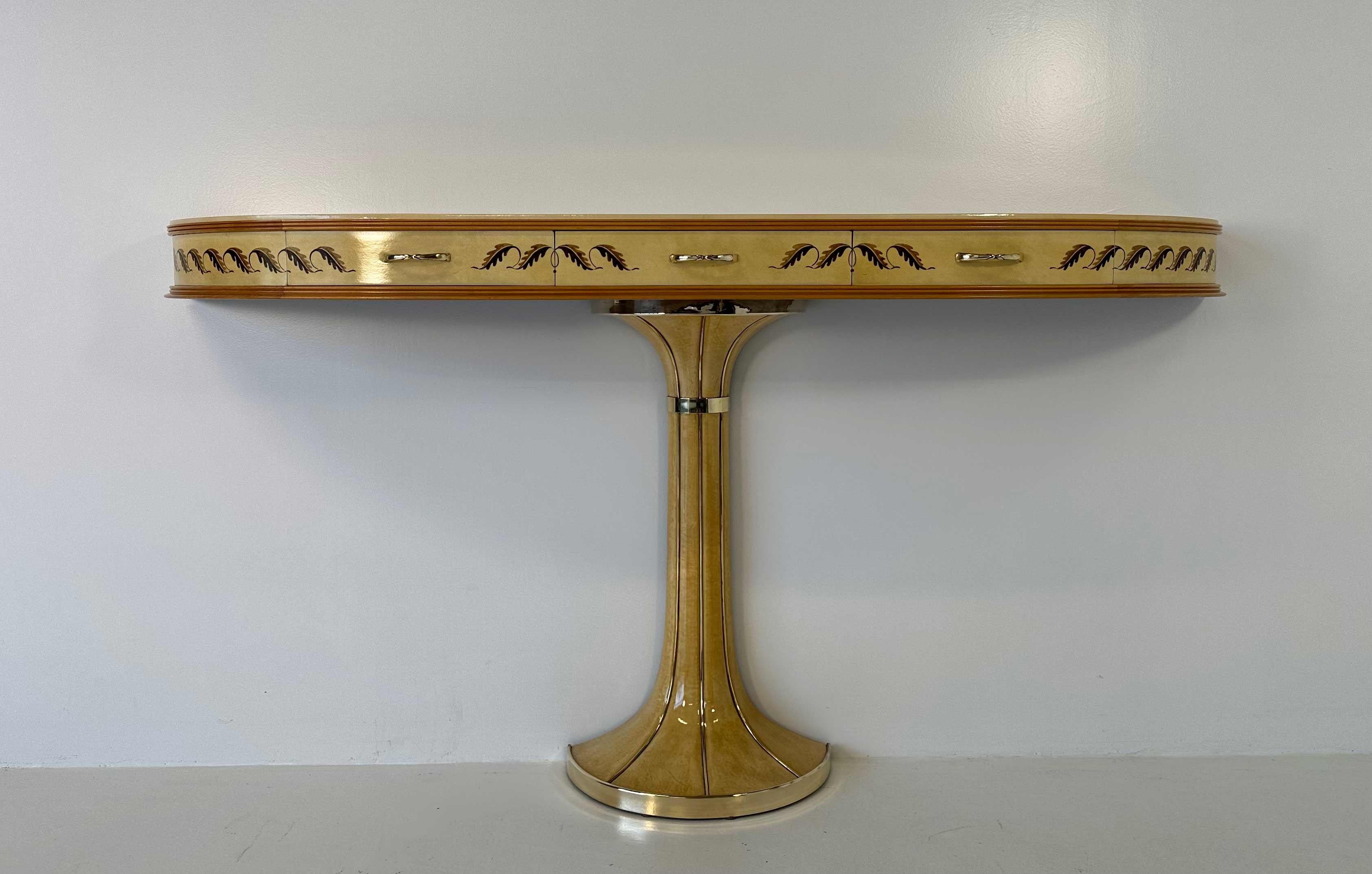 This console was produced in Italy in the end of the 1940s by Vittorio Dassi. 
The top and the base are in original parchment, the profile of the top is in maple and it is decorated with painted leaves. There are three little drawers and the