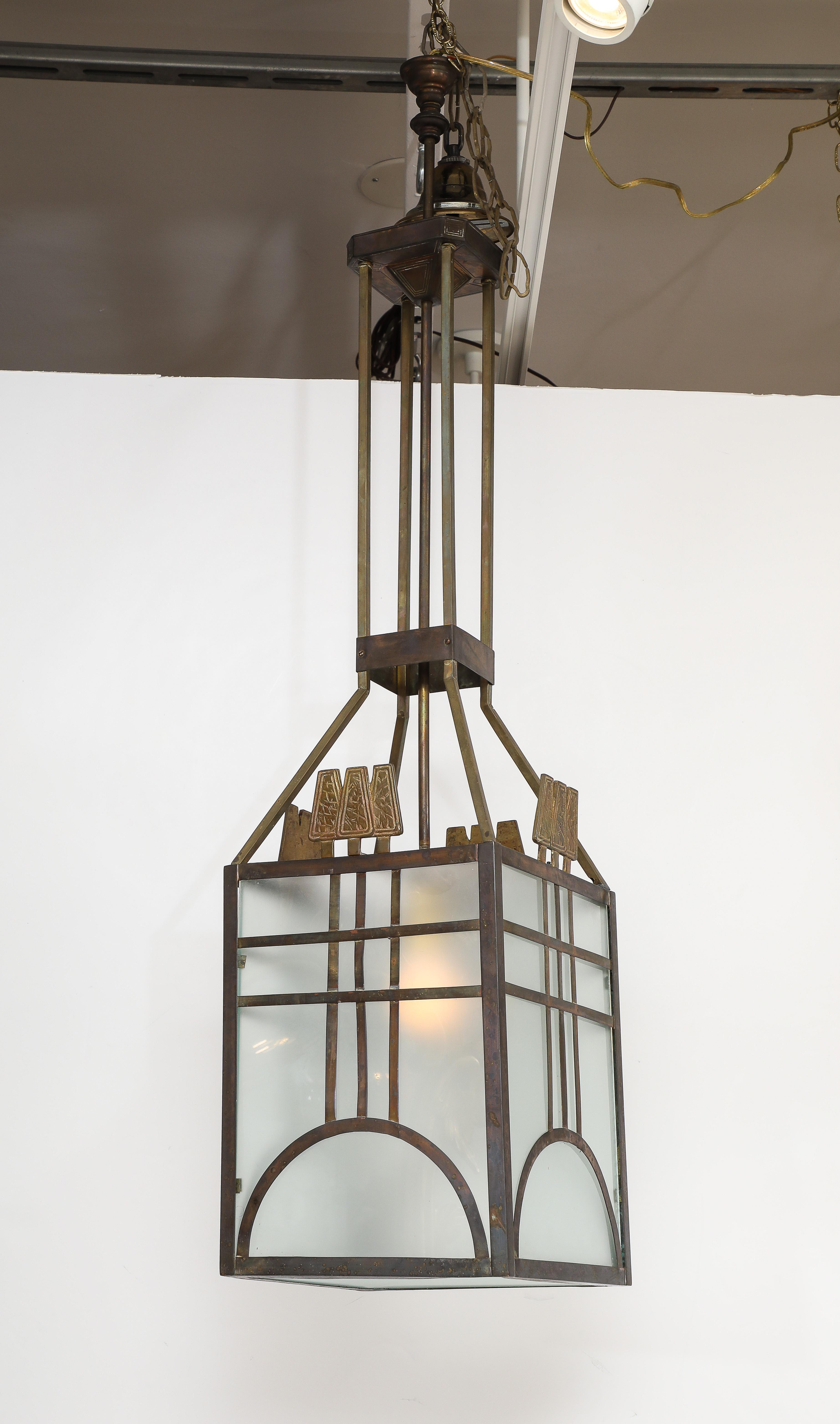 An Italian metal and opaline glass Italian Art Deco period lantern with brass decorative accents atop each square side panel.  The square body is supported by a set of four square stems and one central stem.  With wonderful geometric metal