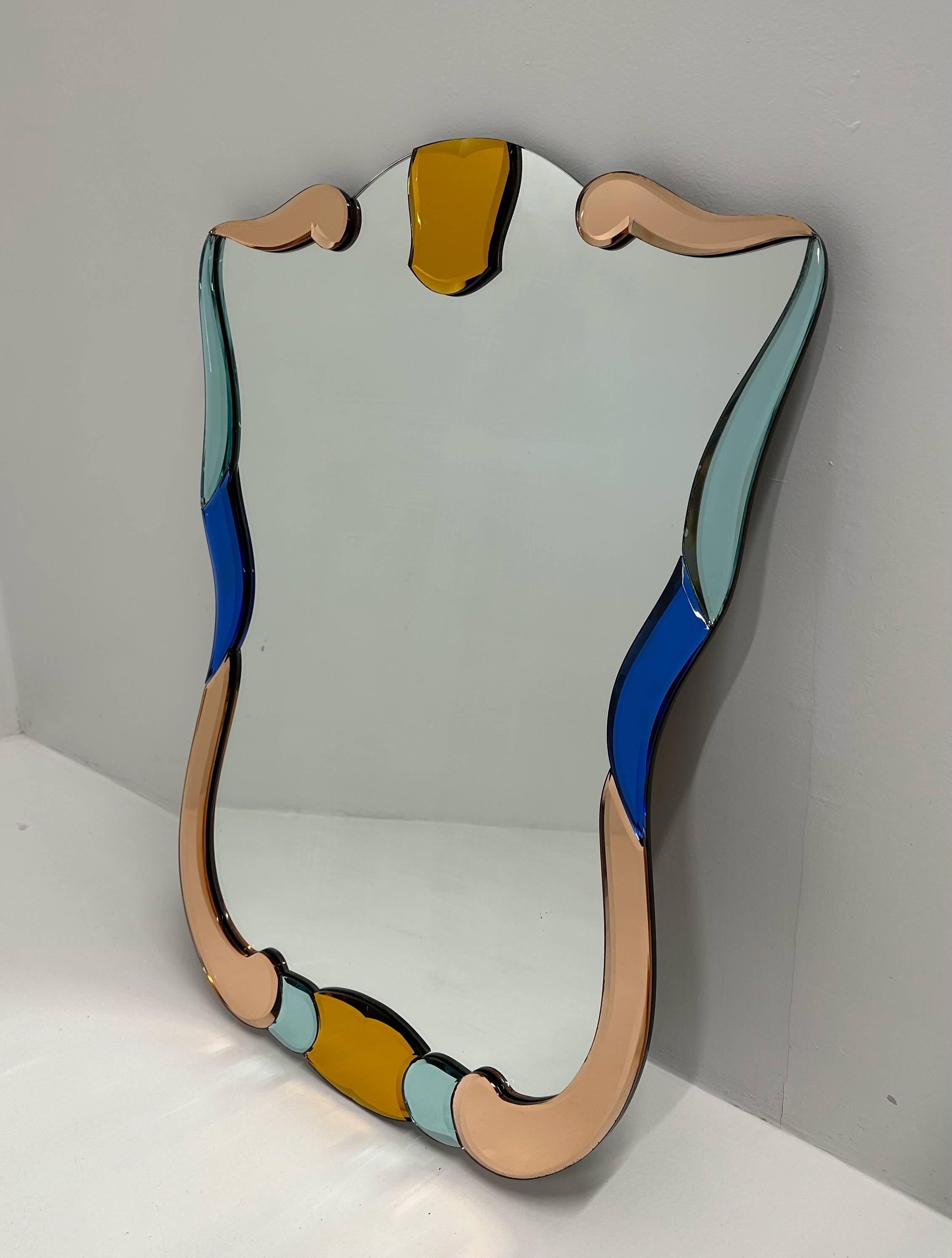 Cet élégant miroir a été produit en Italie, plus précisément à Murano (près de Venise, c'est la capitale mondiale de l'artisanat du verre) dans les années 1980. Le miroir central est encadré par des miroirs de Murano de couleur pastel et de formes
