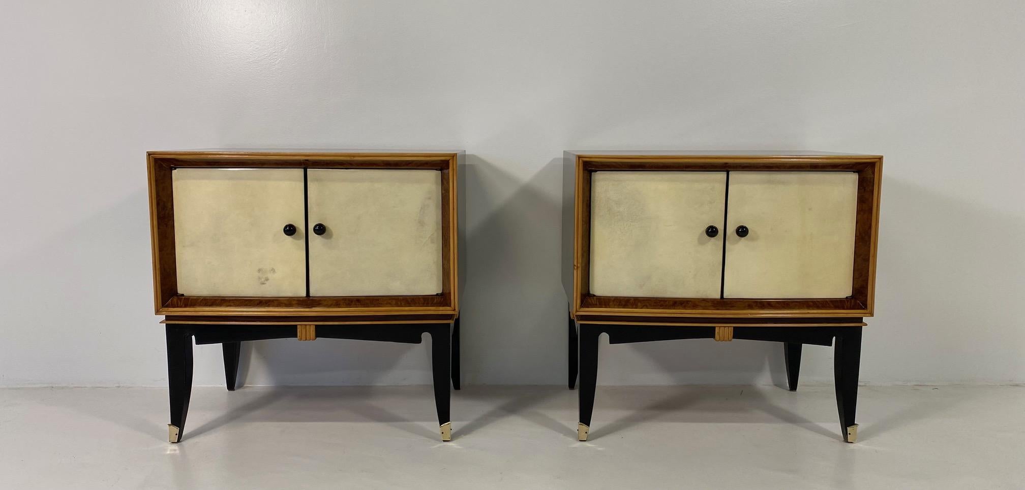 This pair of Art Deco nightstands was produced in Italy in the 1940s.
The two doors are covered in parchment and are framed by a briar walnut profile, which is also framed by a profile in maple. 
Also the profile and the decorations on the black