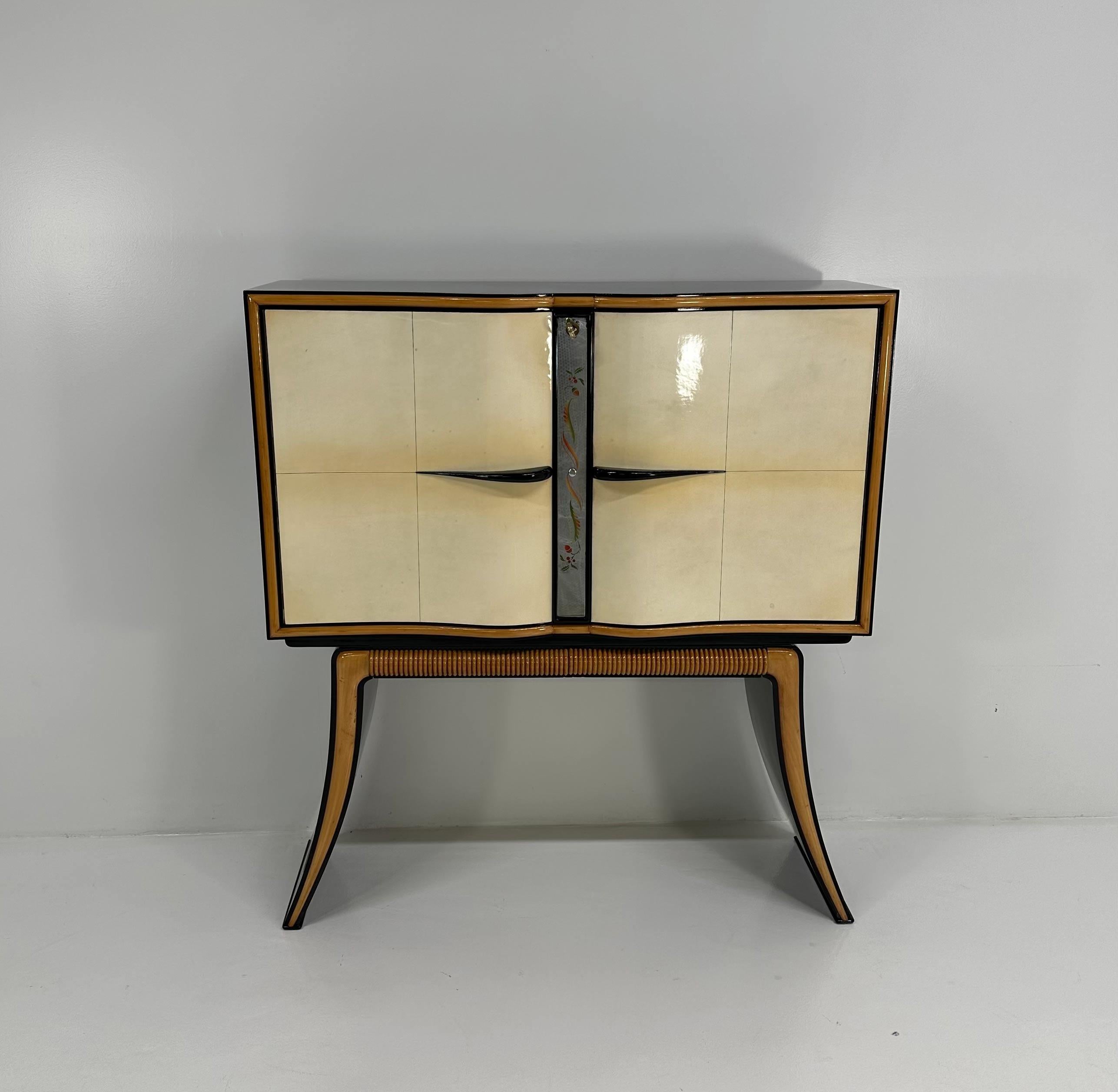 This precious and unique bar cabinet was produced in Italy in the 40s by Paolo Buffa.
The doors are in parchment, the profiles on the legs are in solid maple while the structure is black lacquered.
The front of the cabinet and the inside of the