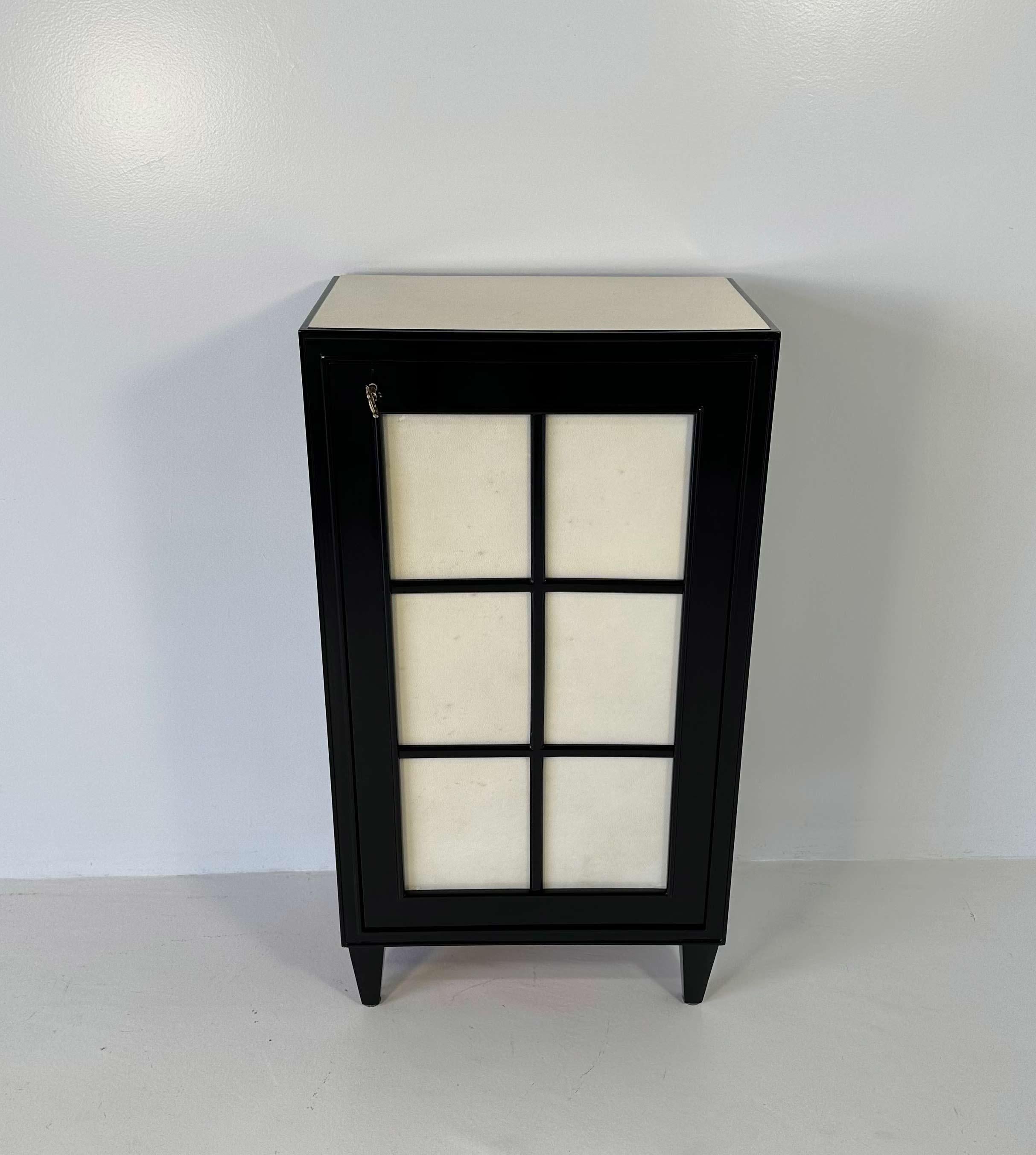 Ce petit meuble Art déco a été produit en Italie dans les années 1940. 
Il est entièrement laqué noir, tandis que la porte et le dessus sont en parchemin. Les clés et le trou de serrure sont en laiton. 
Entièrement restauré.