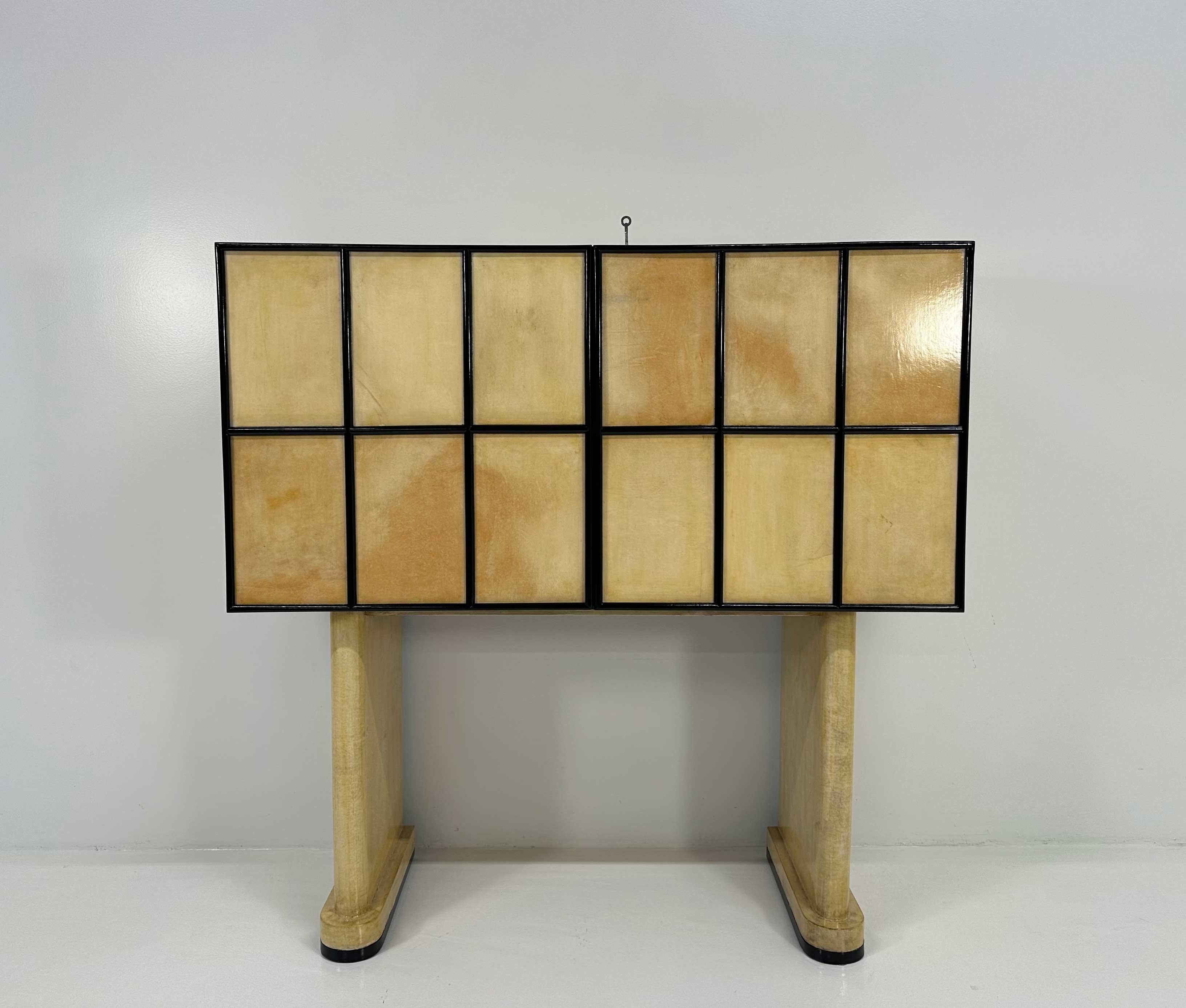 This Art Deco cabinet was produced in Italy in the 1930s. It is completely covered in parchment and has a black lacquered wood geometric decoration. Also the lower profiles of the legs are black lacquered. The interiors are in maple. 
Completely