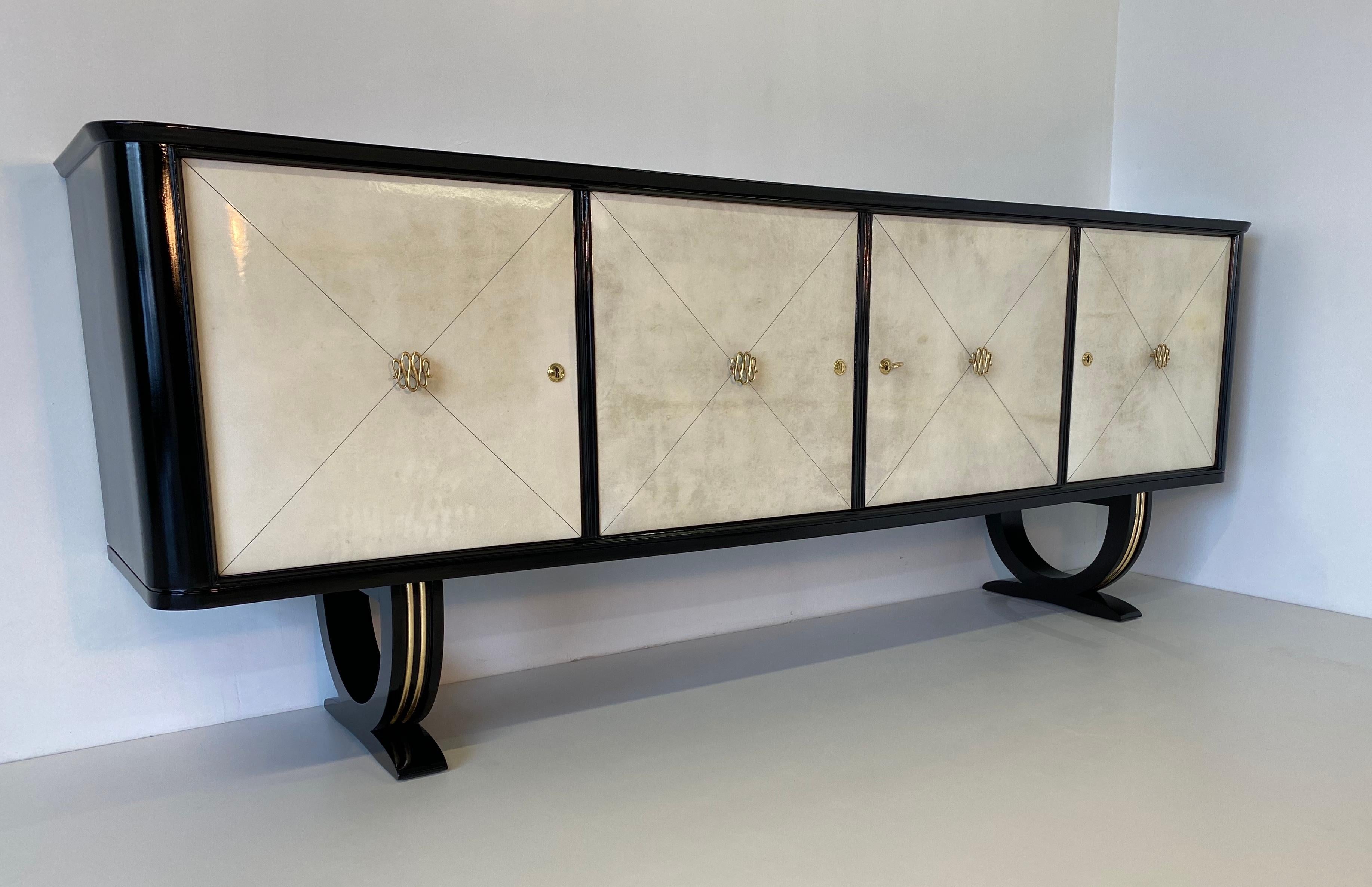 This sideboard was produced in the 1940s in Italy.
The structure is black lacquered while the doors are covered in parchment. 
The details on the base are in gold leaf and the elegant handles are in brass.
Completely restored.