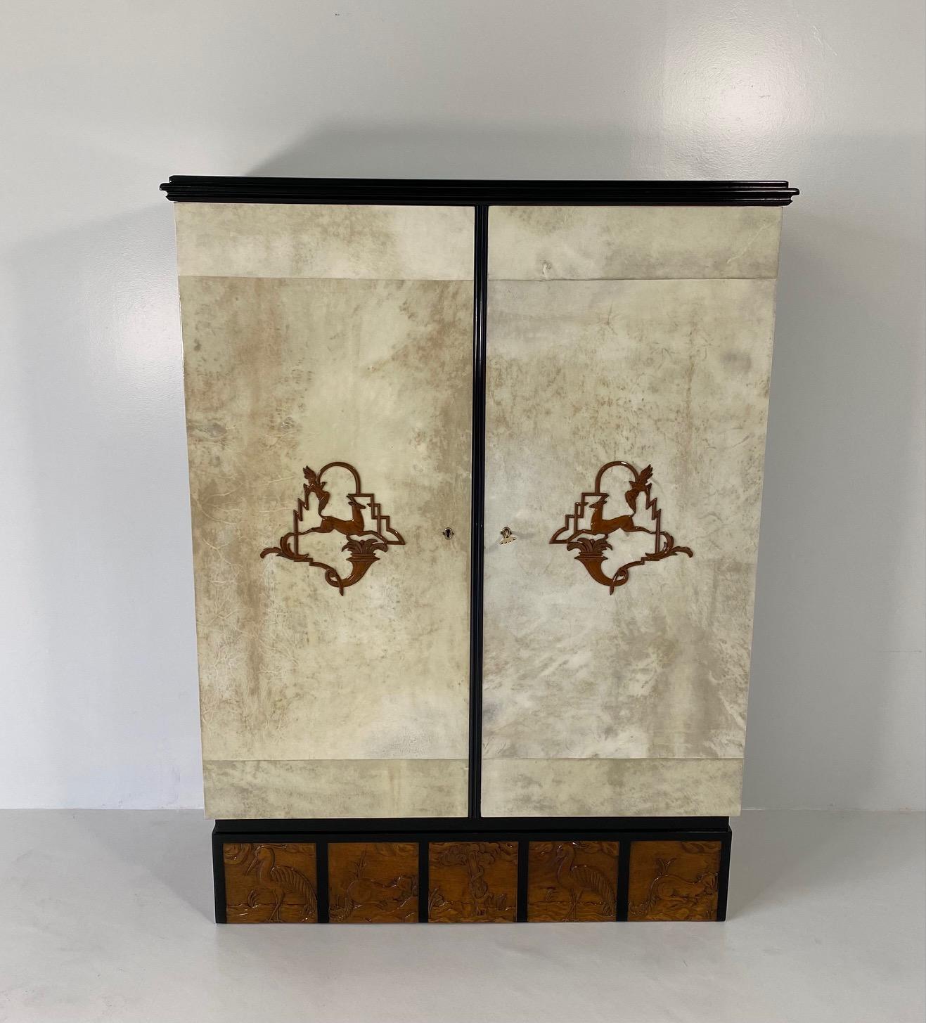 This elegant Art Deco cabinet was produced in Italy in the 1930s. 

The two grand doors are covered in parchment, framed by black lacquered top and profiles and enriched by the presence of two walnut inlay decorations. 

The stunning base is