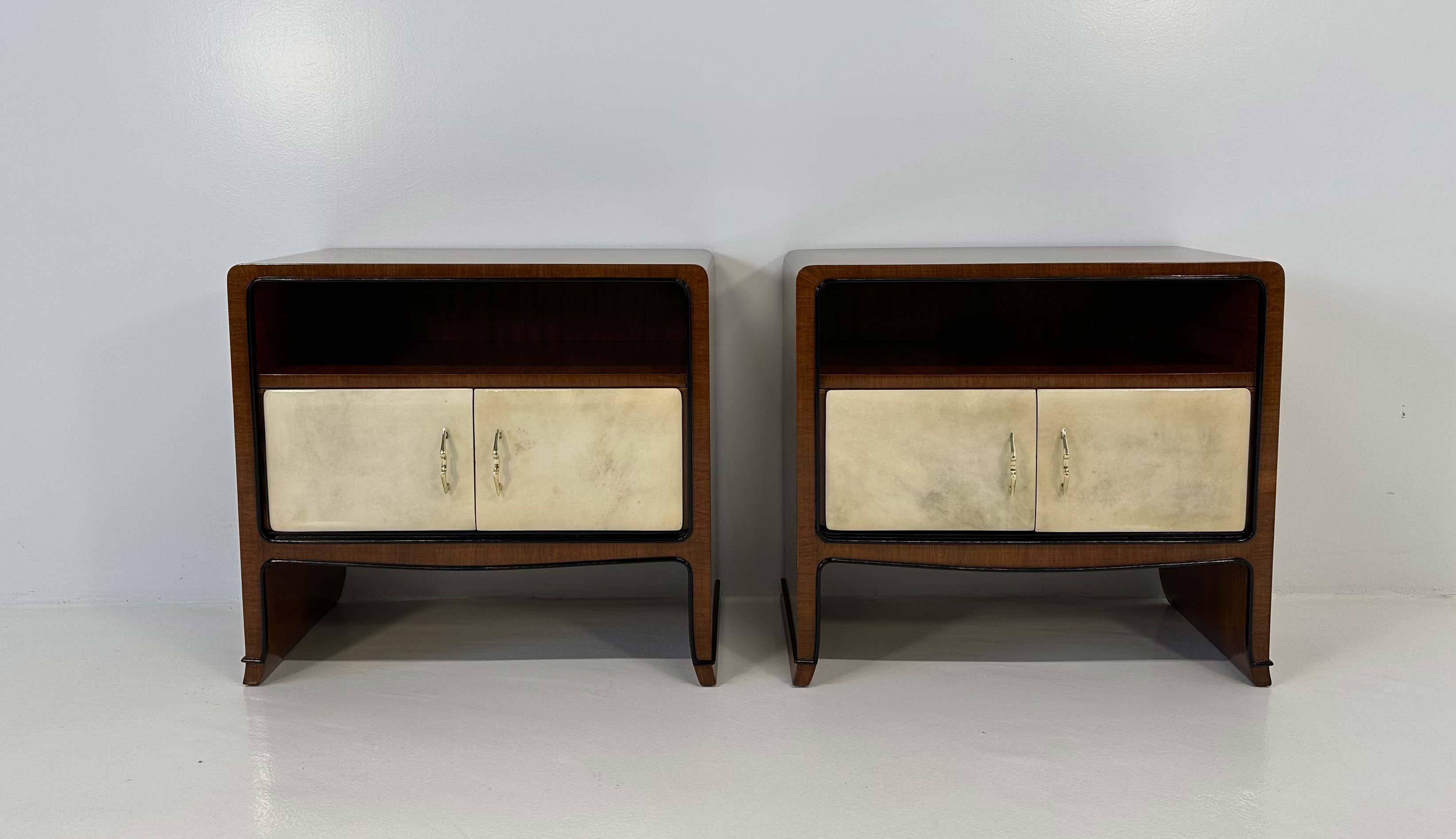 This elegant pair of Art Deco nightstands was produced by Paolo Buffa in the end of the 1940s. They are in walnut wood, with parchment door and black lacquered details, such as the profiles. The beautiful handles are in brass. 
Completely