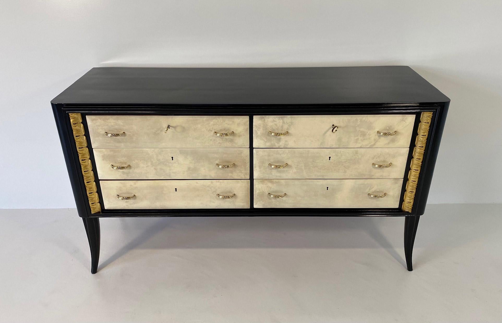 This Art Deco dresser was produced in Italy in the 1940s.

This dresser features six parchment drawers with a black lacquered structure and two gold leaf decorations. 

The handless are in brass.


