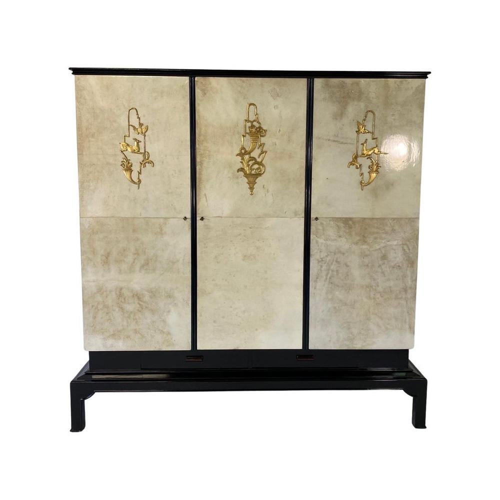 This stunning Art Deco wardrobe was produced in Italy in the 1930s. 
The laterals and the doors are in parchment, with gold leaf decorations and black lacquered profiles and base. 
On the interiors there are both shelves and a cloth hanger tube,