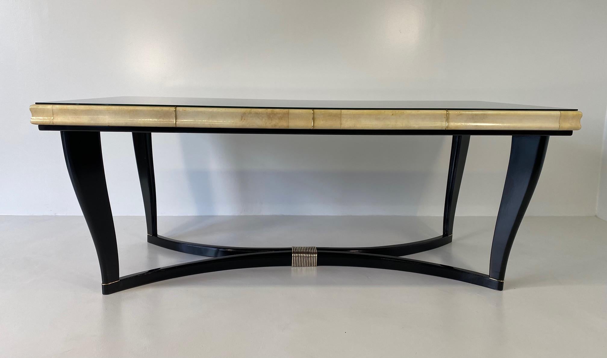 This Art Deco table was produced in Italy in the 1940s. 

The top is in black glass, framed by a parchment edge, the elegant legs and the base are black lacquered with a central brass decoration. 

Completely restored.