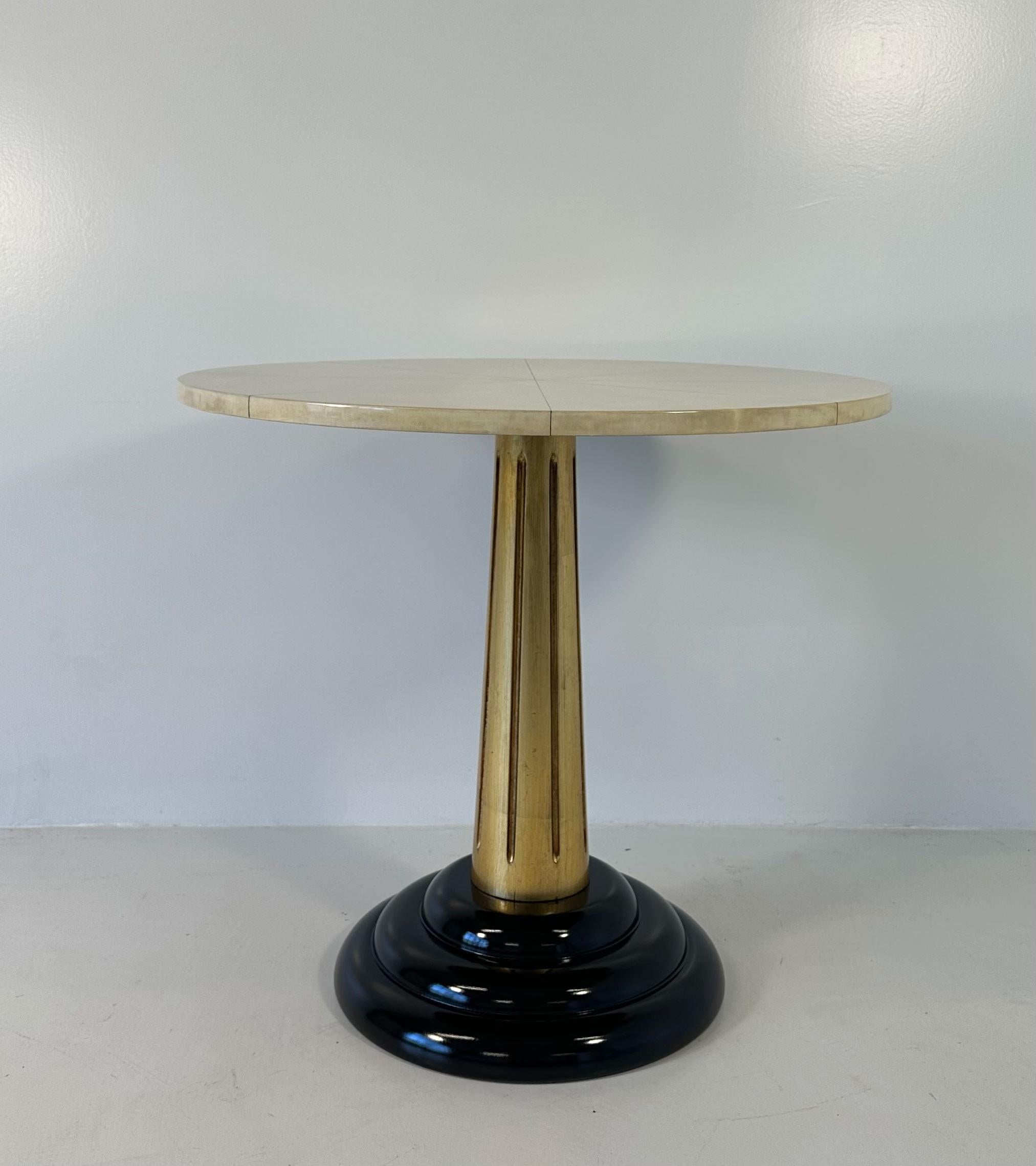 This Art Deco style coffee table was produced in Italy in the 1980s. 
The top is in parchment, the column leg is in gold leaf and the base is black lacquered. 
Completely restored. 

