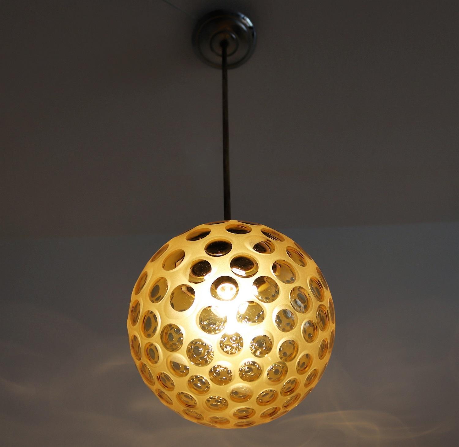 Gorgeous small pendant lamp with beautiful frosted cut glass sphere and metal details.
Made in Italy, 1940s
The amber-yellow glass is cut with many round windows within the glass sphere and makes beautiful reflects when illuminated.
All parts are