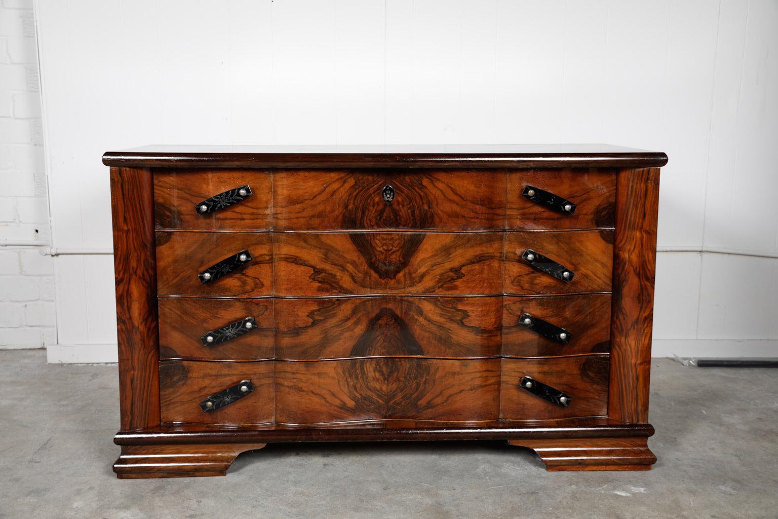 Early 20th century Italian Art Deco Period commode covered in a fine quality palisander veneer that has been bookmatched. The case holds four inset scalloped drawers with beautiful black etched handles set on a diagonal. The case is raised on molded