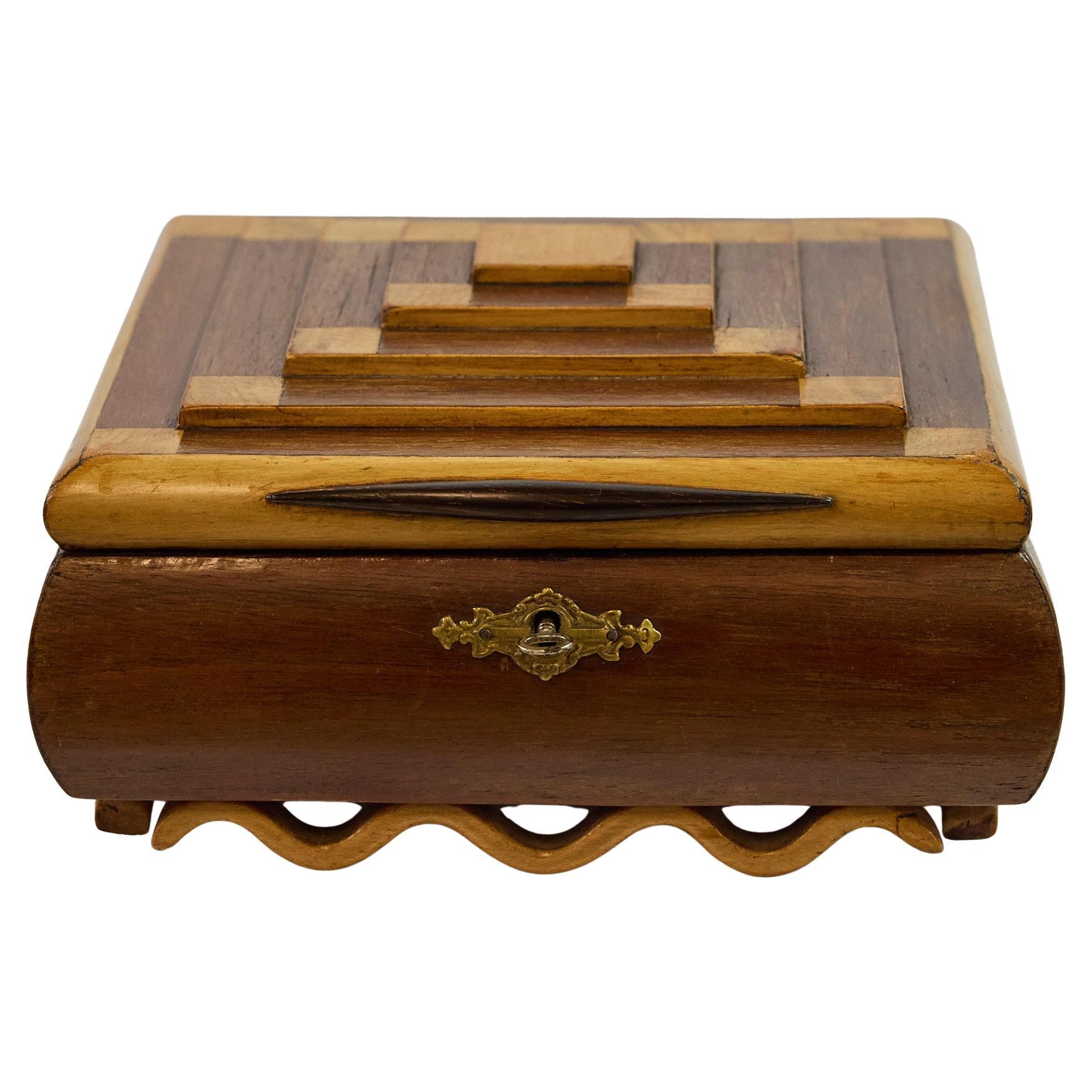 This is a charming Art Deco period jewelry or trinket box, dating to circa 1920s-1930s, showcasing the era's distinctive geometric design and fine craftsmanship.
The box features an eye-catching lid composed of mixed hardwoods arranged in a striking