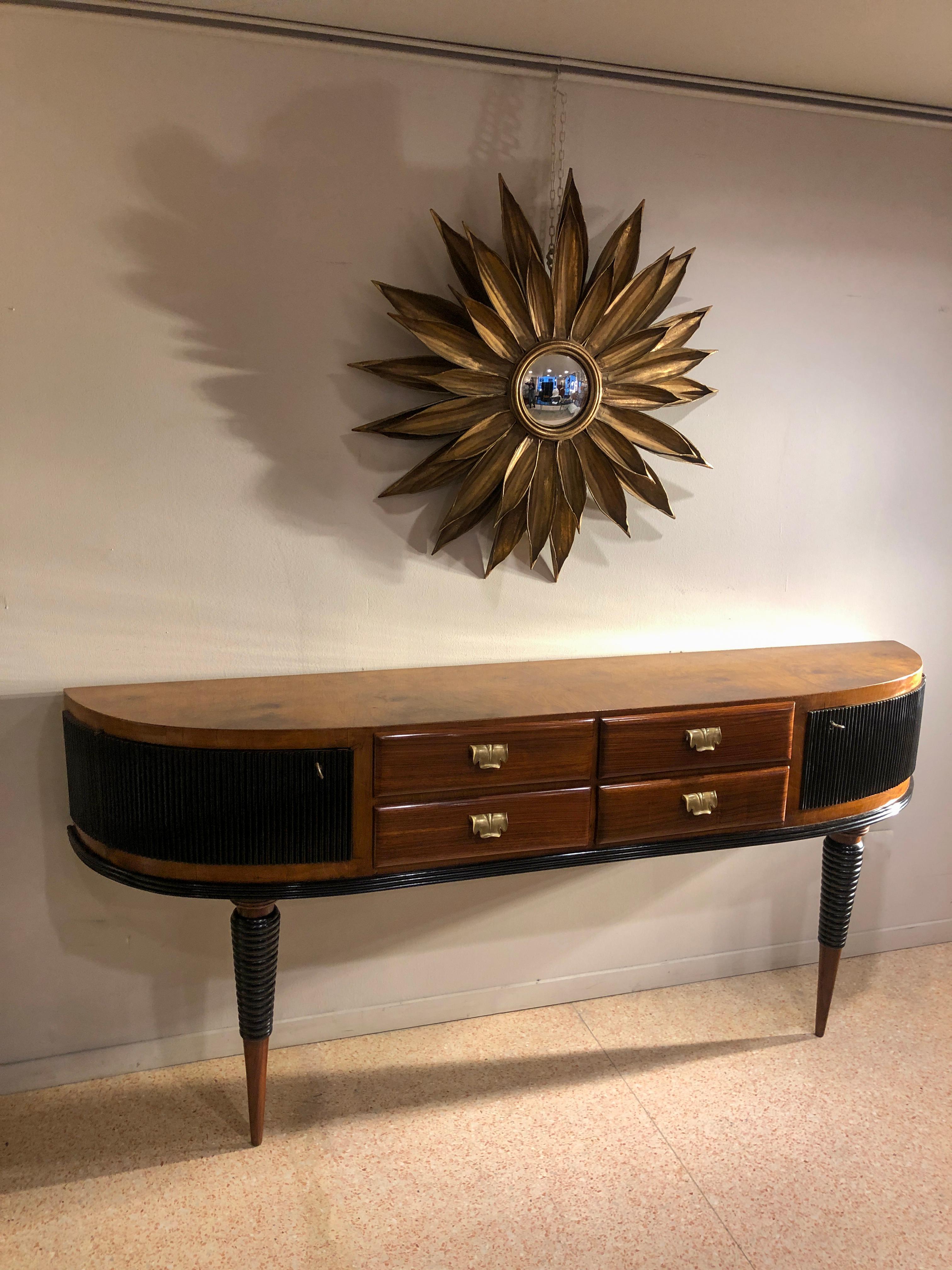 Art Deco rosewood table console credenza with rounded edges doors and four drawers with brass leaves shapes handles. There are some black lacquered ebonized parts such us the legs and the curved doors. The console measures D 38 cm, L 200 cm, H 90