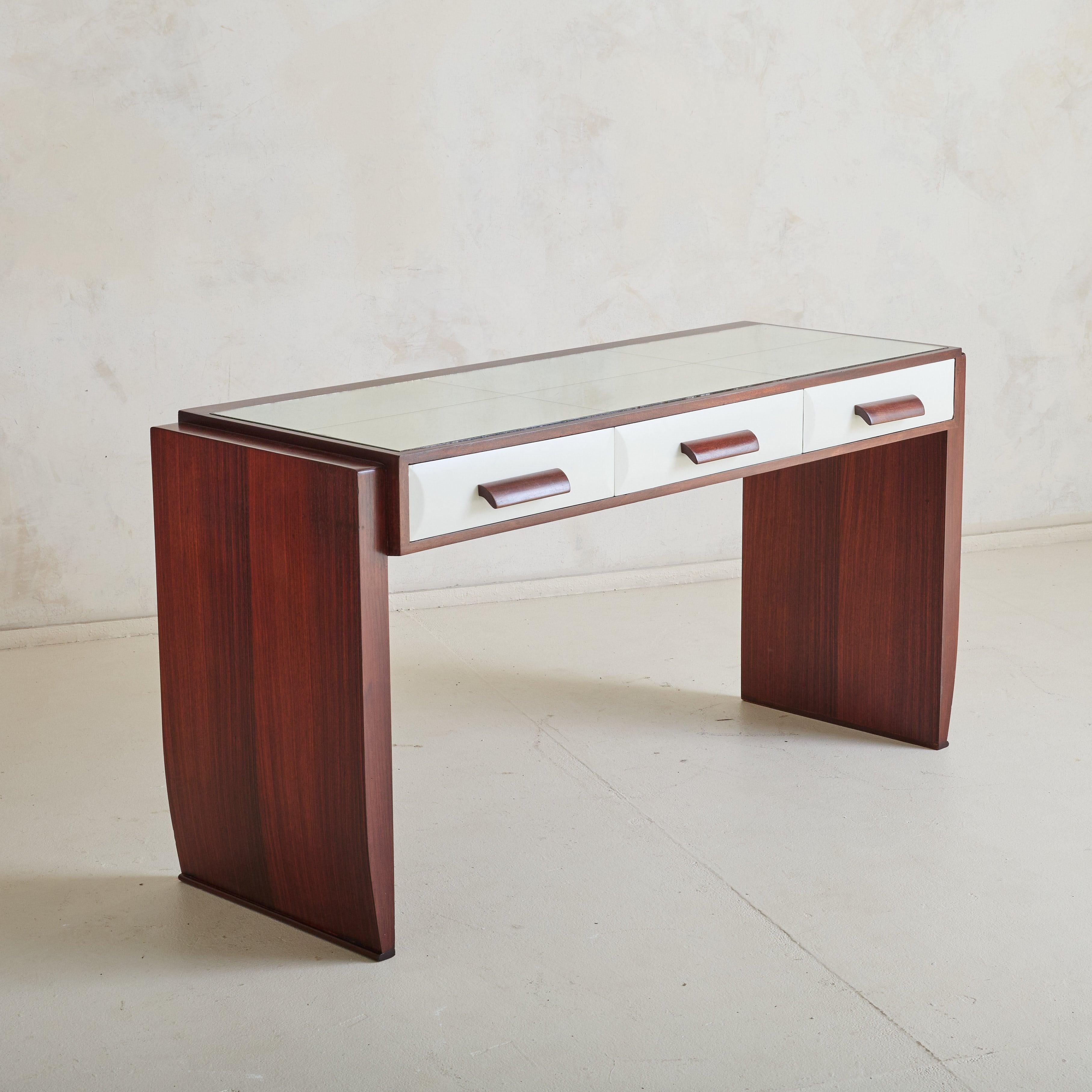 An Italian Art Deco vanity from the 1940s, reminiscent of designs by Osvaldo Borsani. Crafted from rich rosewood veneer, this piece is defined by sculptural legs with graceful inward curves, grounding the piece in architectural poise. The three