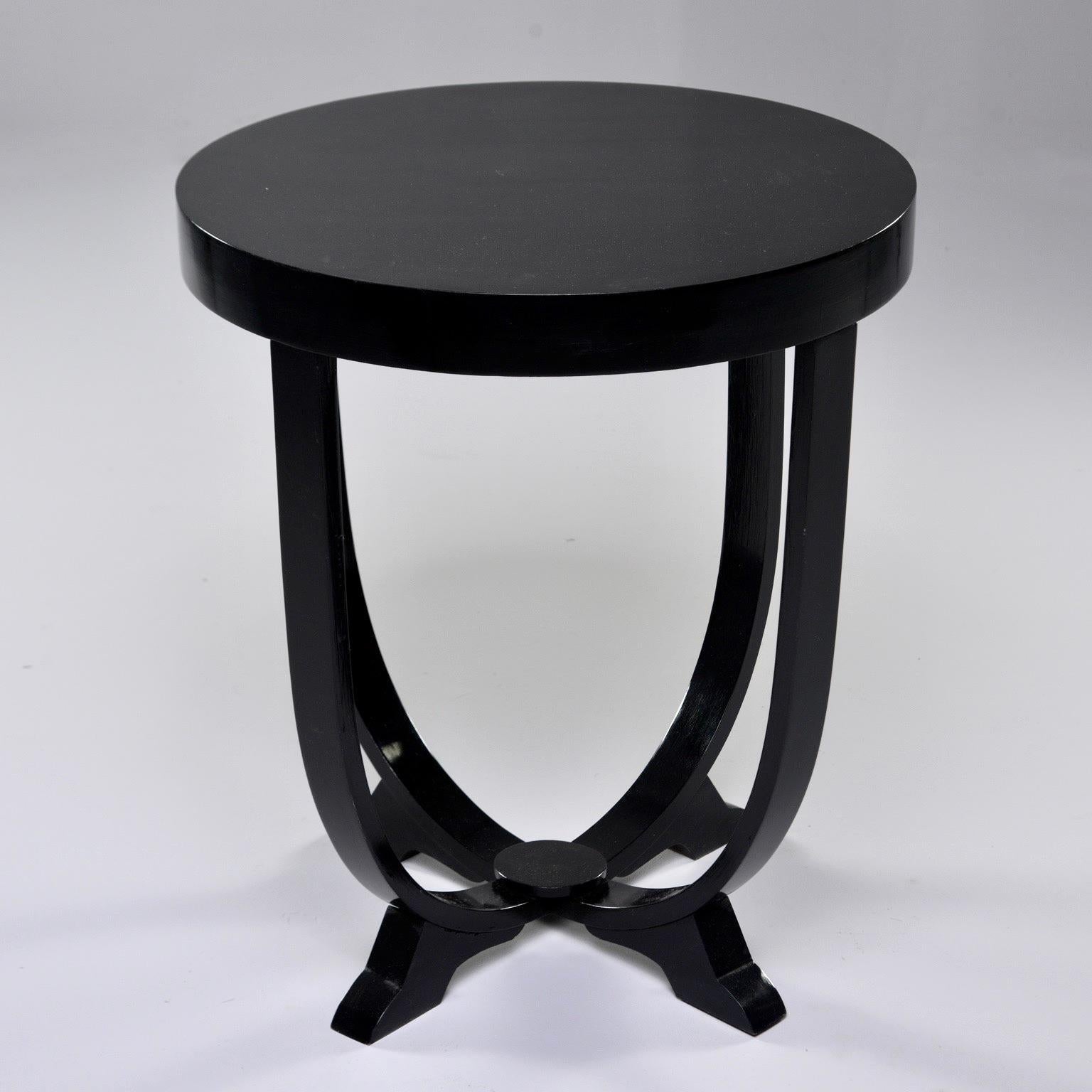 Italian Art Deco era side or center table features a round tabletop, four curved legs that join at a footed base, circa 1930s. New professionally applied ebonized finish. Unknown maker.