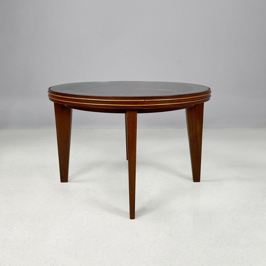 Art Déco italiano Mesa de centro redonda de madera con tapa de cristal, años 30
Mesa de centro con tapa redonda de cristal que descansa sobre una estructura de madera oscura. Tiene cuatro patas de base rectangular que se estrechan hacia la parte