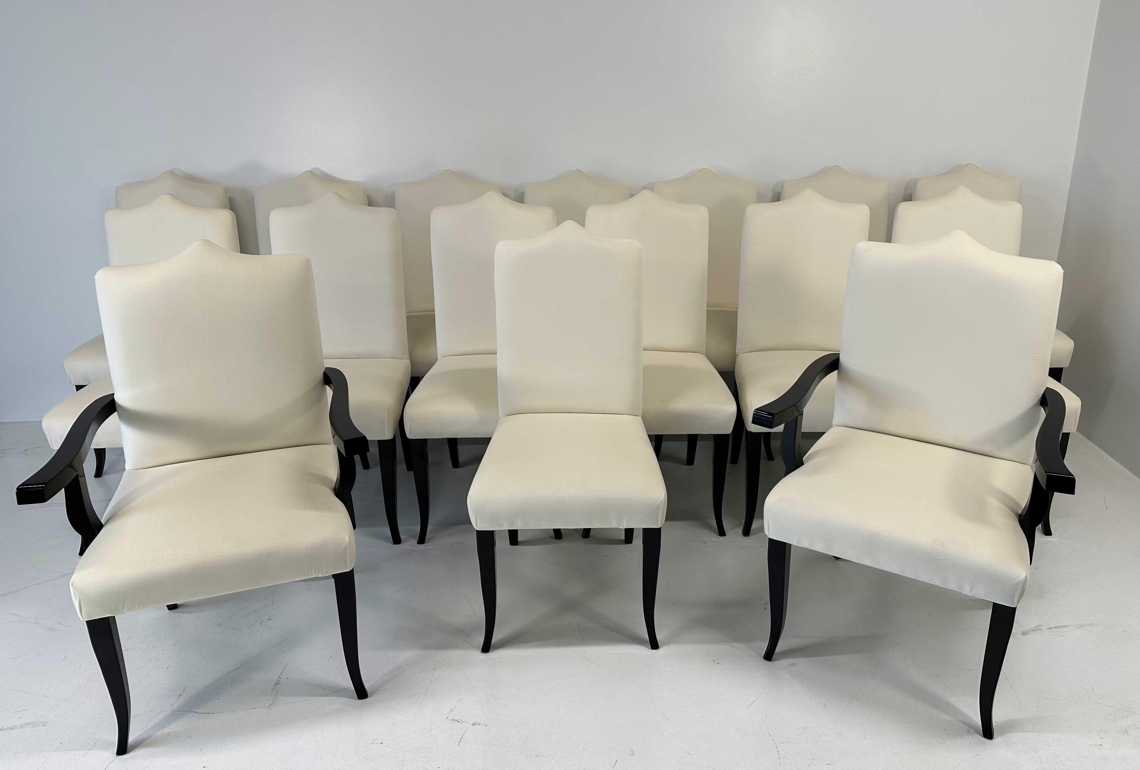 This set of 16 Art Deco style chairs is actually composed by 14 chairs and 2 thrones (chairs with arms for the heads of the table) . They were produced in the north of Italy in the 1980s. 
They are completely covered in an high quality cream velvet