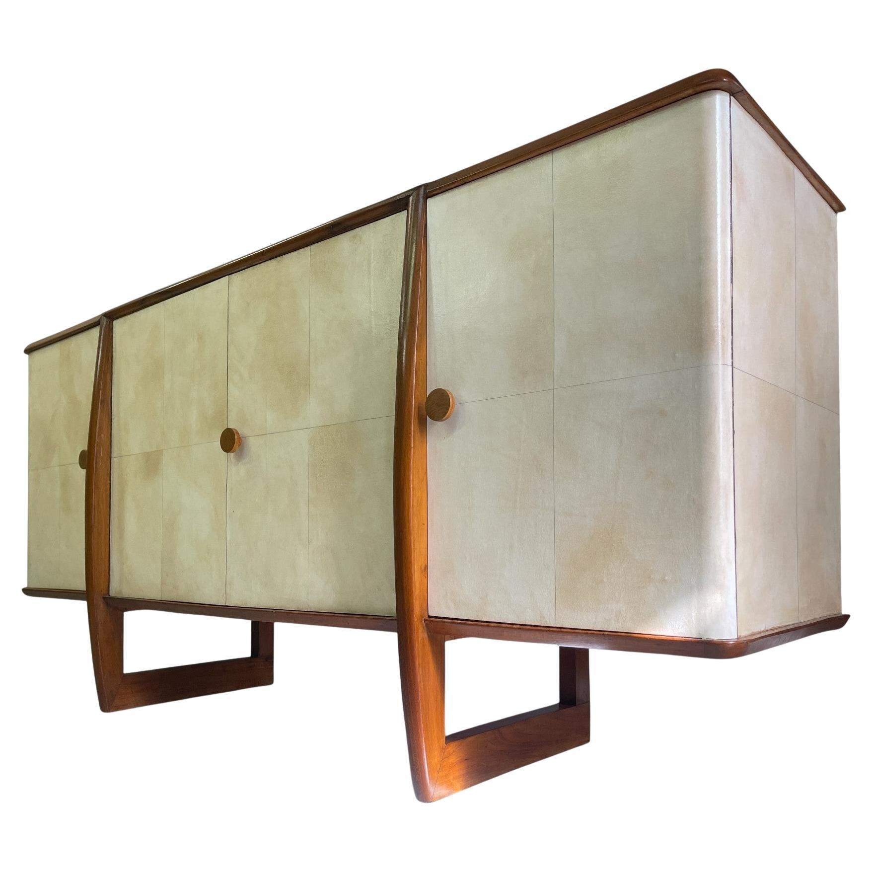 This elegant Italian sideboard from the 1940s exemplifies the perfect balance between structural rationality and formal softness, hallmarks of late Italian Art Déco. Crafted in solid walnut and clad in natural parchment, the piece stands out for its
