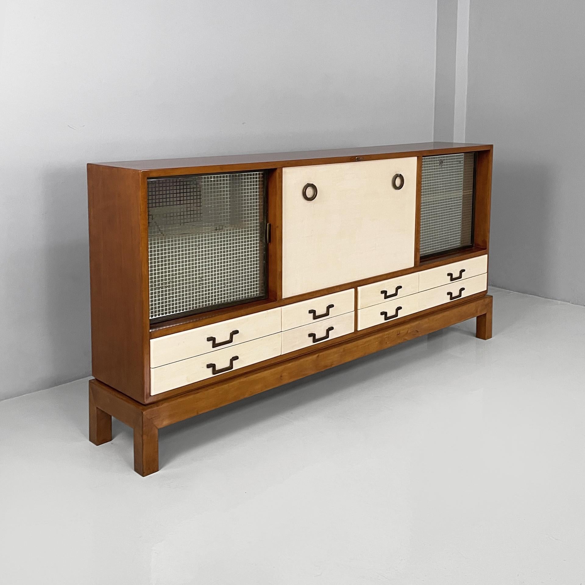 Italian Art Deco sideboard in wood, brass and glass, 1940s
Rectangular sideboard in wood and glass. In the upper section there are two compartments with hinged glass doors with checked pattern, a internal wooden shelf and brass handles. The central