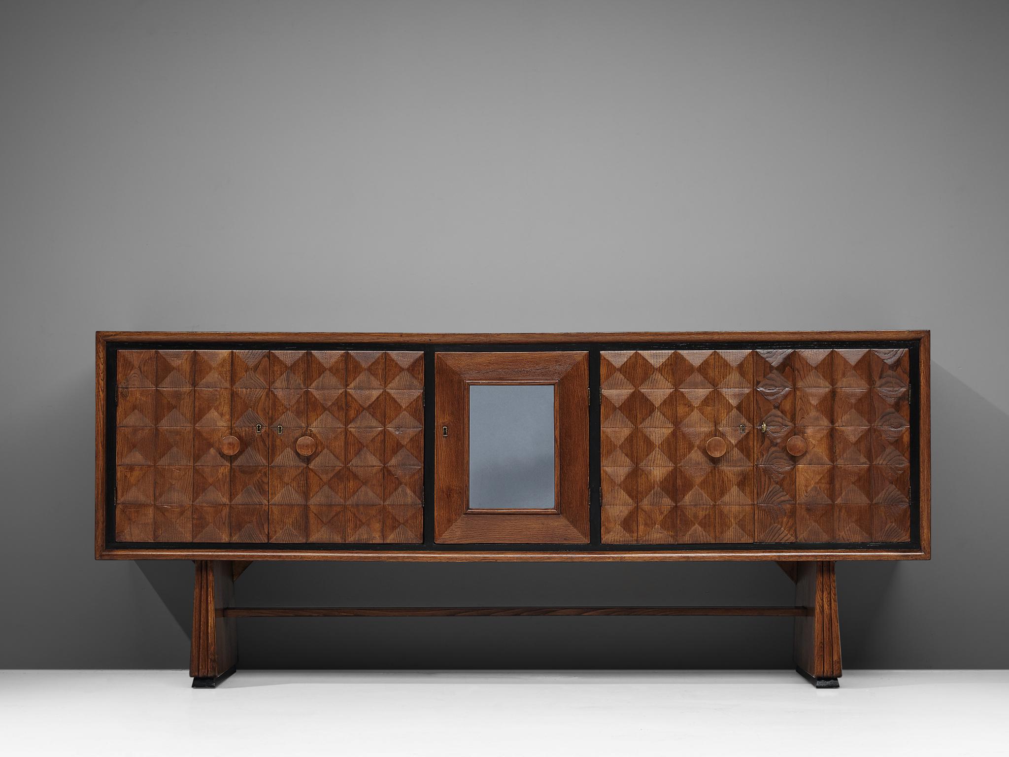 Art Deco sideboard, oak, brass, and glass mirror, Italy, 1940s

Delicate and playful Italian sideboard with graphical doors. Over connected trapezoid legs stands a cabinet with five doors. The middle is accentuated with a mirror. Highlight is the