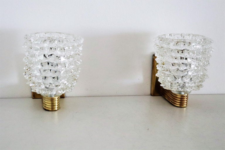 Beautiful set of two gorgeous heavy wall lamps entirely hand-crafted in Murano made of clear Murano glass in rostrato technique.
The glasses are fixed on hand-crafted brass plate.
Made in the Art Deco style of Barovier and Toso.
The brass is with