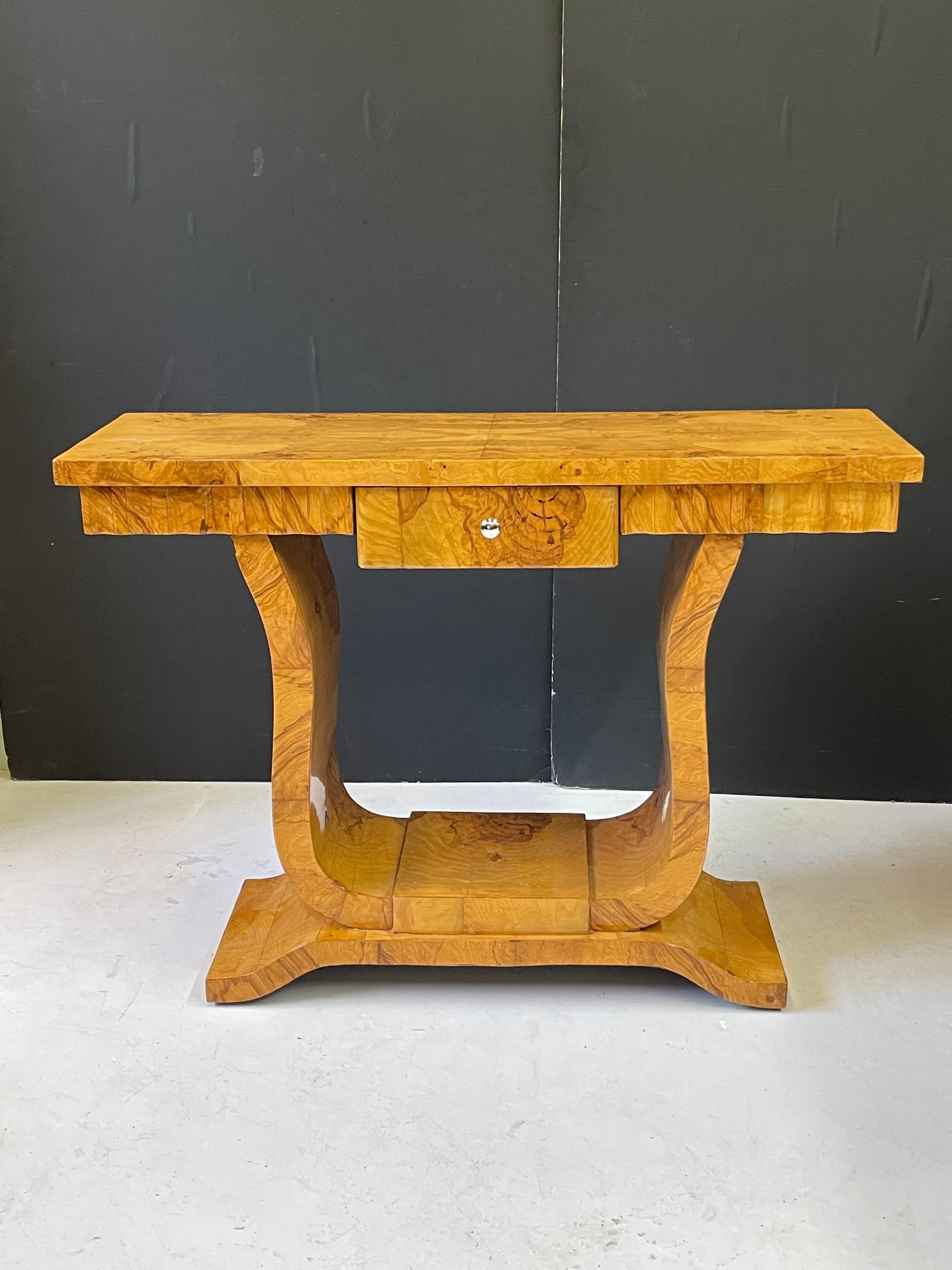 This is an incredible 20th century Italian console table designed in the style of Art Deco and constructed of a striking birch burl veneer. The rectangular top holds a center drawer in its frieze (accented with chrome hardware) and is surrounded on