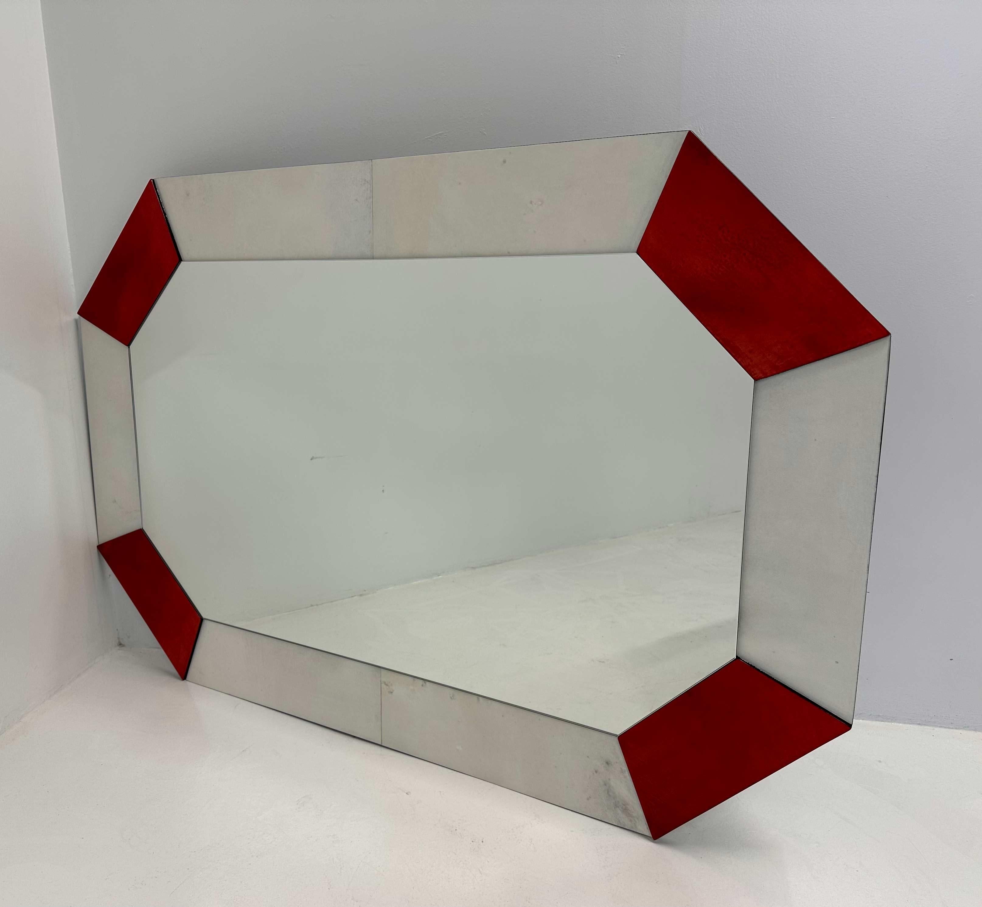 Este espejo de estilo Art Déco se fabricó en Italia en la década de 1990. El marco está hecho de trozos de pergamino rojo cereza y blanco.