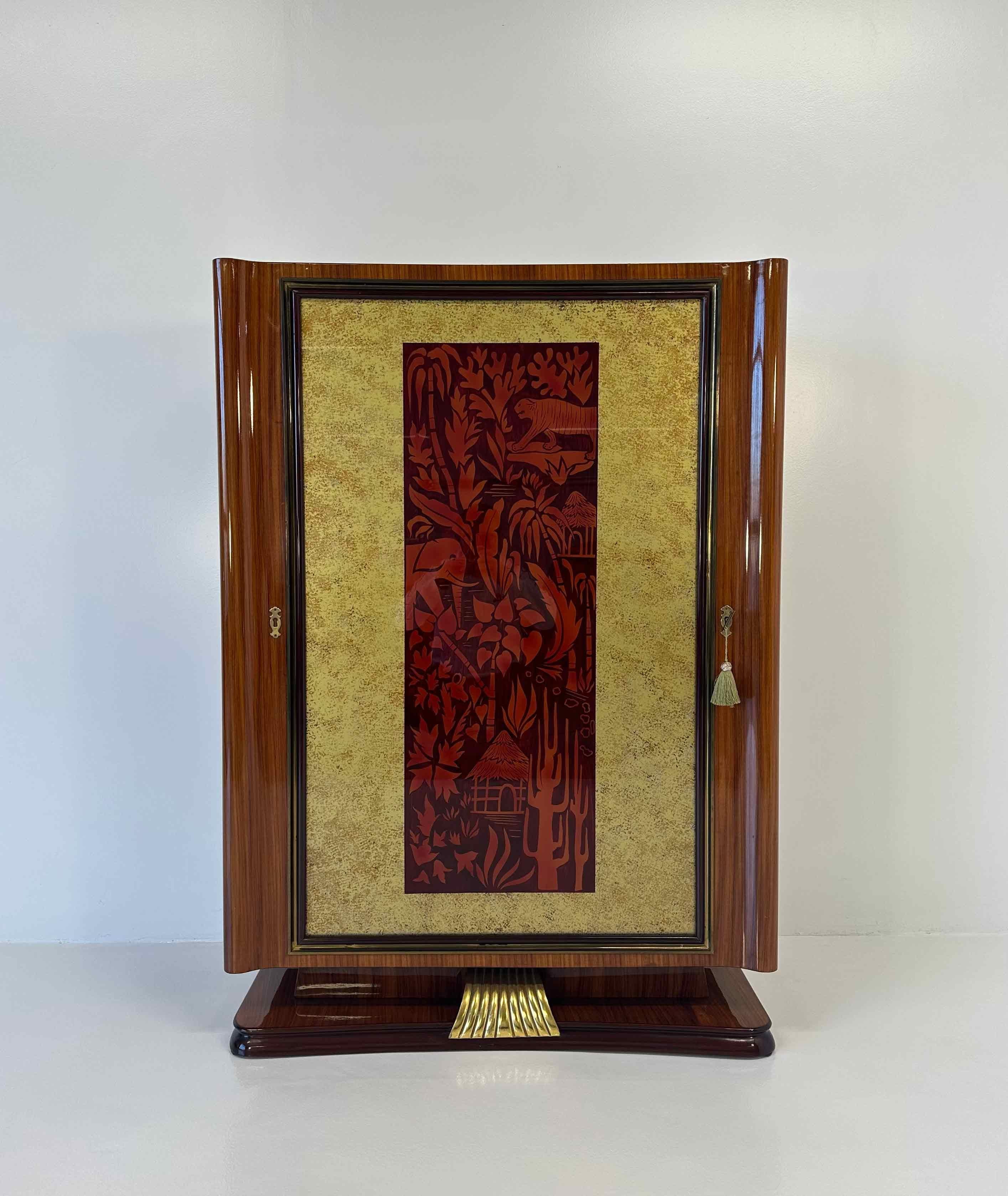This Art Deco Style Dry Bar Cabinet is a real piece of art that belongs to a museum and was produced in Italy in the 1950s by the Vittorio Dassi company. 
The structure is made of a fine exotic wood, enriched by a gold leafed wood decoration on the