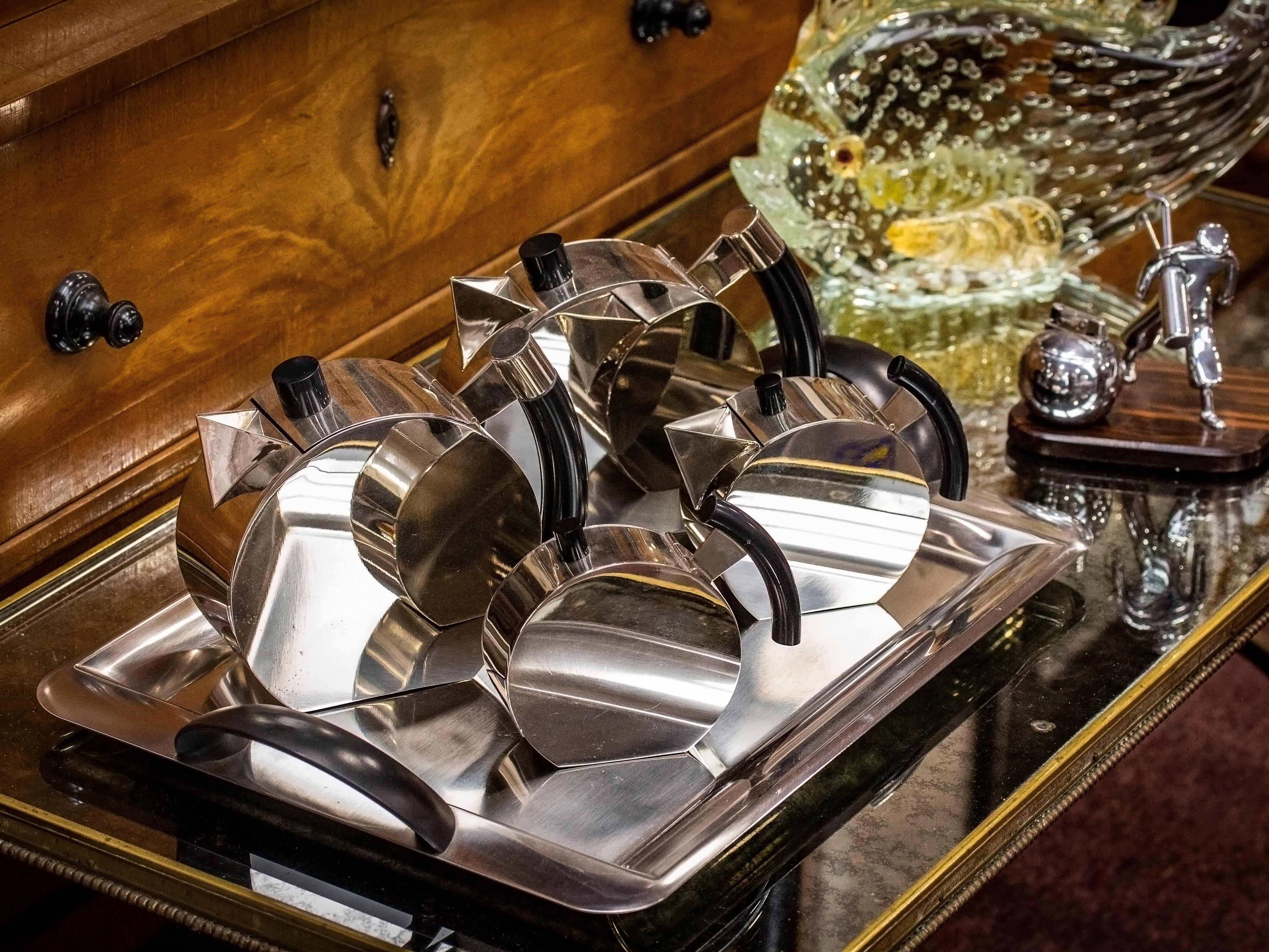 Entworfen von Punta Bacola für Montagnani

Aus unserer Accessories-Kollektion bieten wir Ihnen dieses äußerst stilvolle Teeservice im Art Deco-Stil an. Das Service besteht aus einer Tee- und Kaffeekanne, einem Milchkännchen und einem Zuckergefäß auf