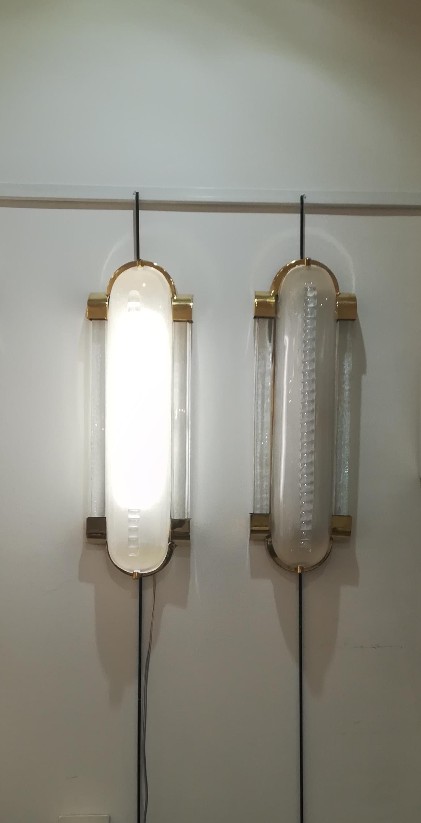 Beautiful pair of brass wall sconces in Murano curved satiny glass. Notches decor.
