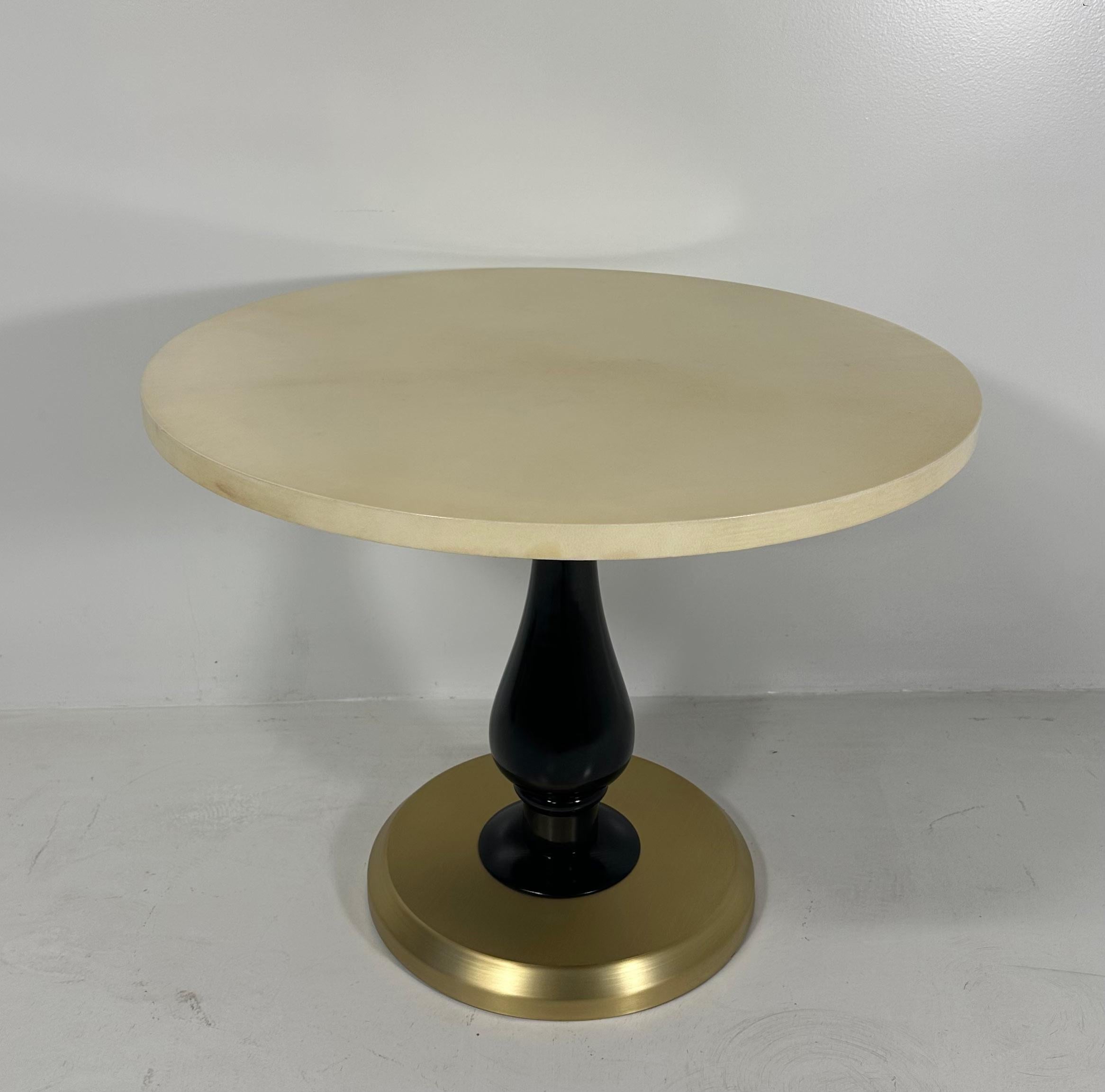 Cette table basse de style Art déco a été produite en Italie dans les années 1980. 
Le plateau est en parchemin, le pied de la colonne est laqué noir et la base est en laiton.
Entièrement restauré. 