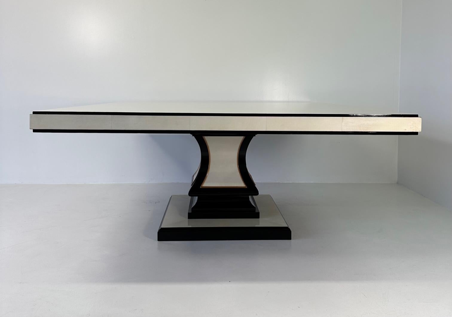 Cette table carrée Art déco a été produite en Italie dans les années 1980.
Le plateau, la base et la colonne centrale sont en parchemin, encadrés par des profils en laque noire et en érable. En particulier, le haut est en carrés de parchemin.