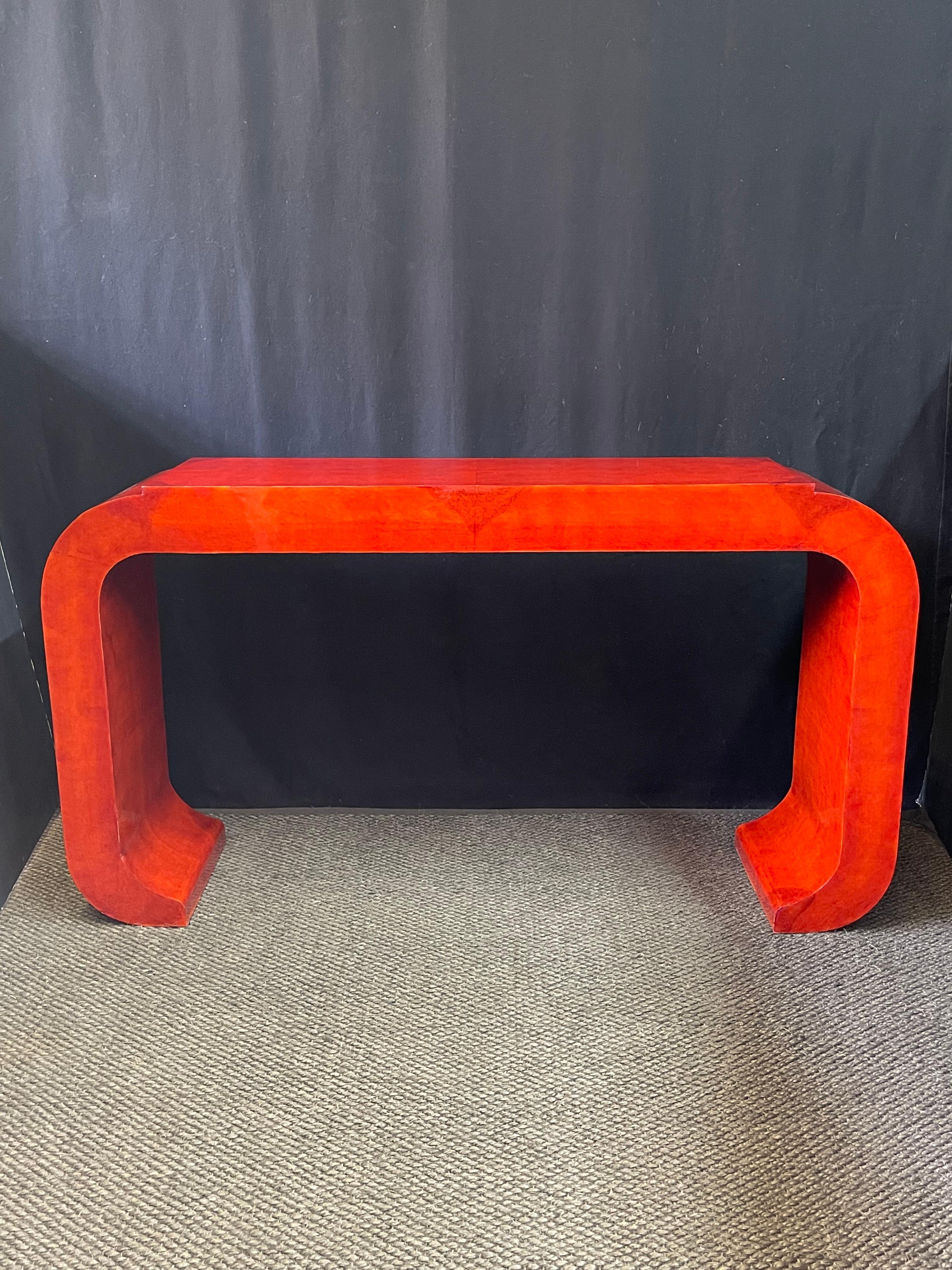 Stunning 21st Century Italian console table created in the manner of Art Deco with curved joints and a raised platform top. The table is finished in a bright and rich red lacquer over a burled wood veneer. It would make an excellent console table as