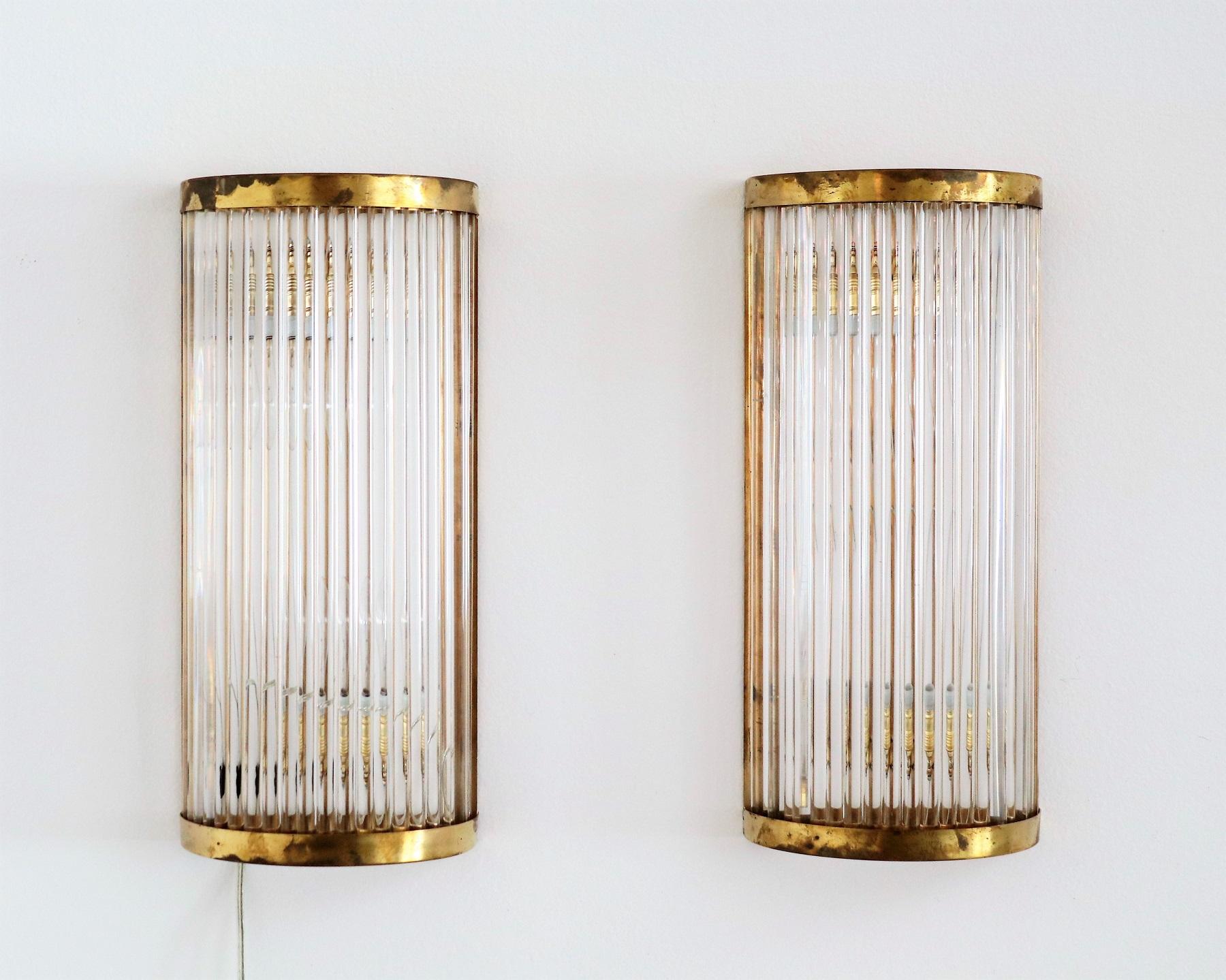 Gorgeous and glamorous big size set of two pieces wall sconces made of long transparent glass rods with full brass frame.
These wall sconces with their timeless design made in Italy in the Art Deco Style are made of excellent craftsmanship and are