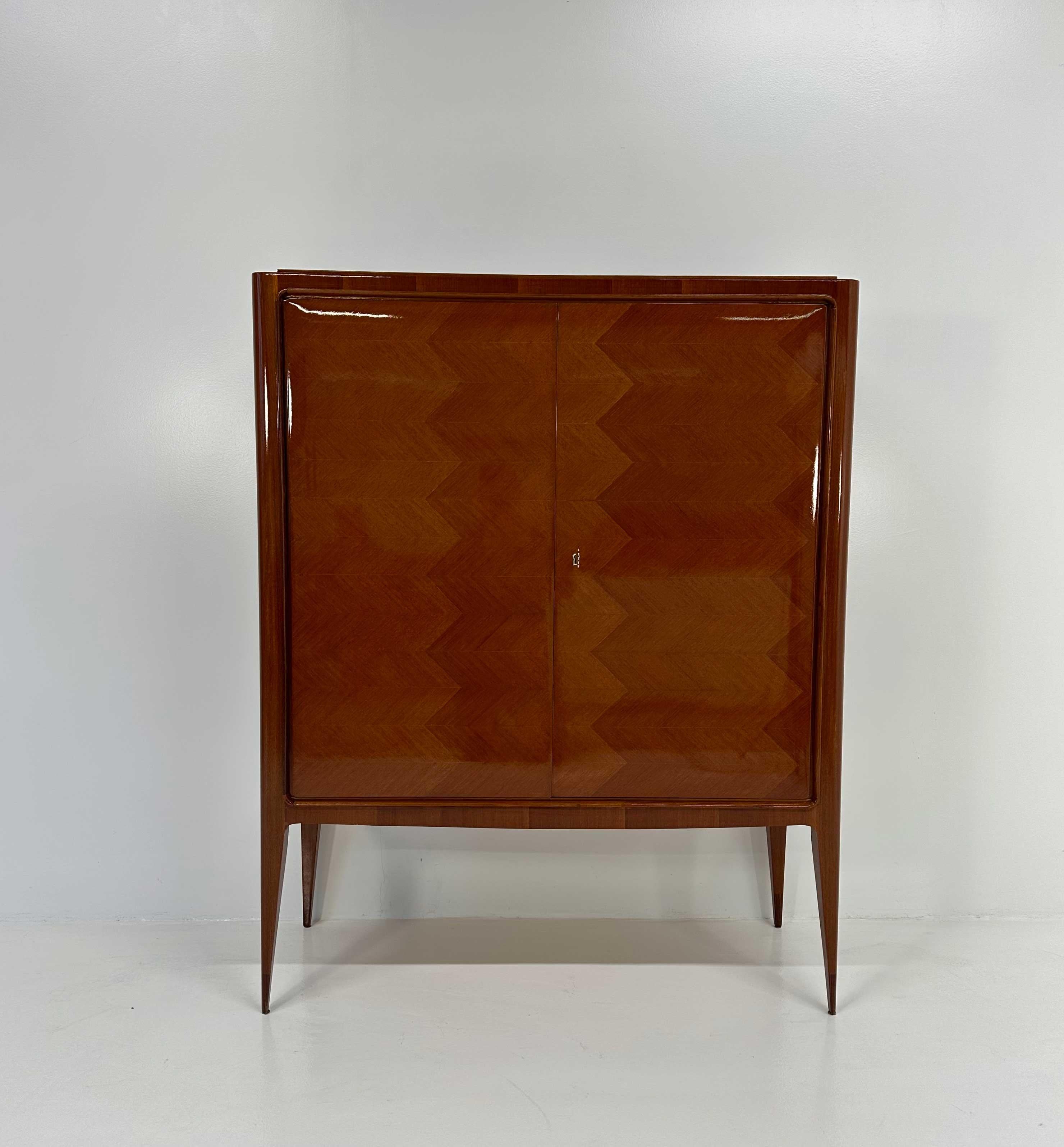 Ce meuble de bar a été produit en Italie dans les années 1950 par Paolo Buffa. 
La structure extérieure est entièrement réalisée en bois de teck. 
La beauté de cette pièce est couronnée par les intérieurs élégants, caractérisés par la présence de