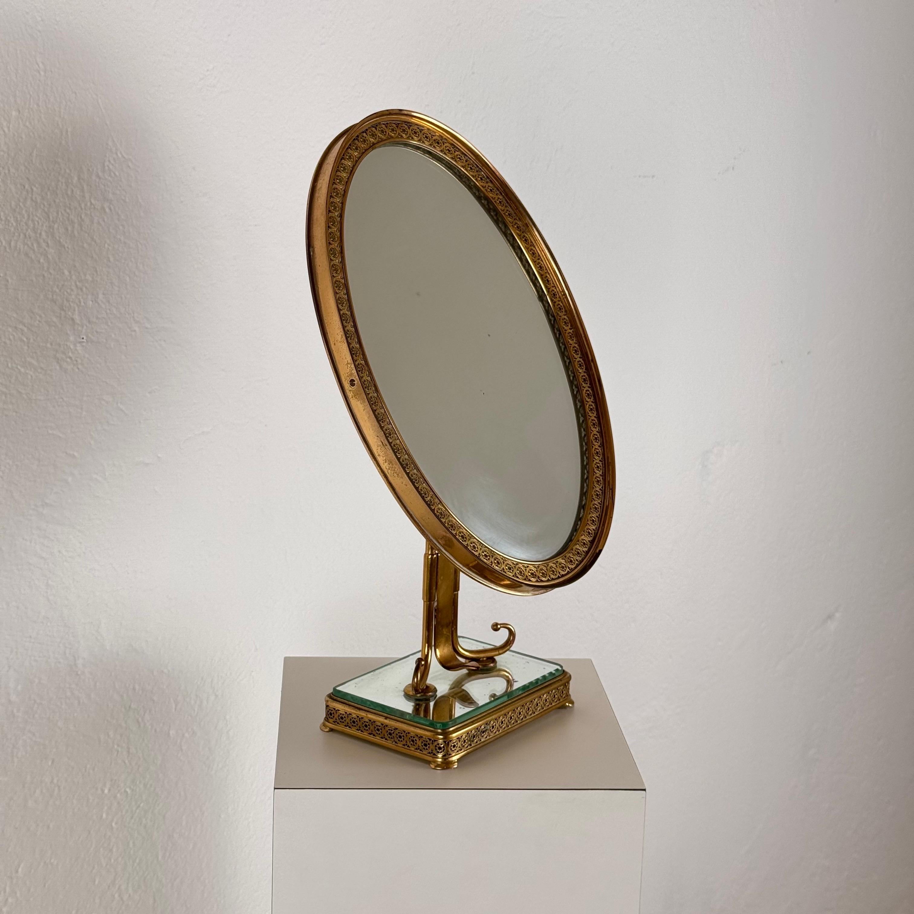 Un excepcional espejo de tocador italiano de la década de 1940, diseñado por Pier Luigi Colli, que muestra una artesanía exquisita y una elegancia atemporal. El espejo presenta un marco de latón bellamente detallado con intrincados trabajos