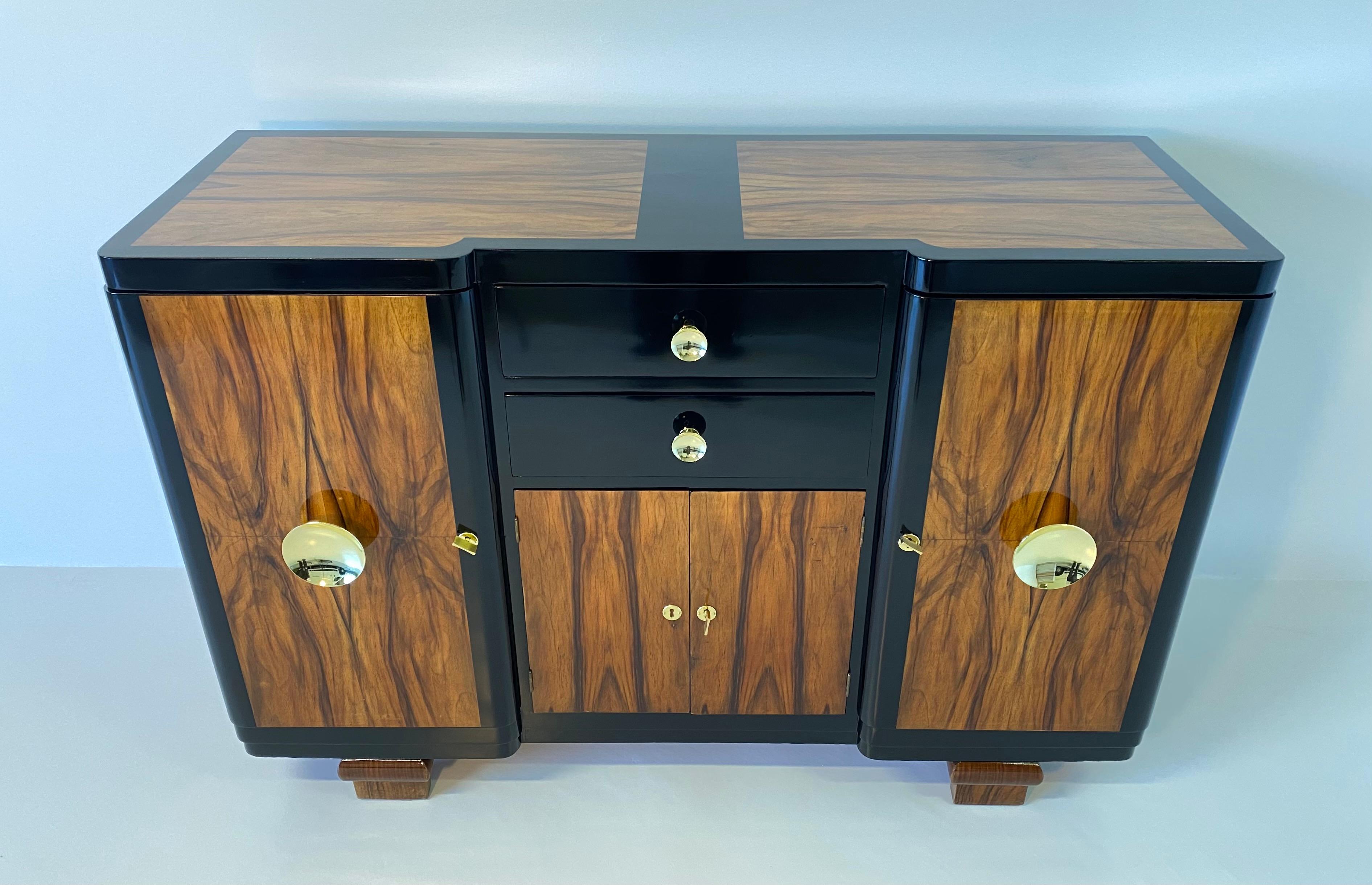 This sideboard was produced in Italy in the 1930s.
It is finely veneered in walnut briar and profiles and drawers are in black lacquered wood.
The imposing handles and keys are made of brass.
Totally restored.