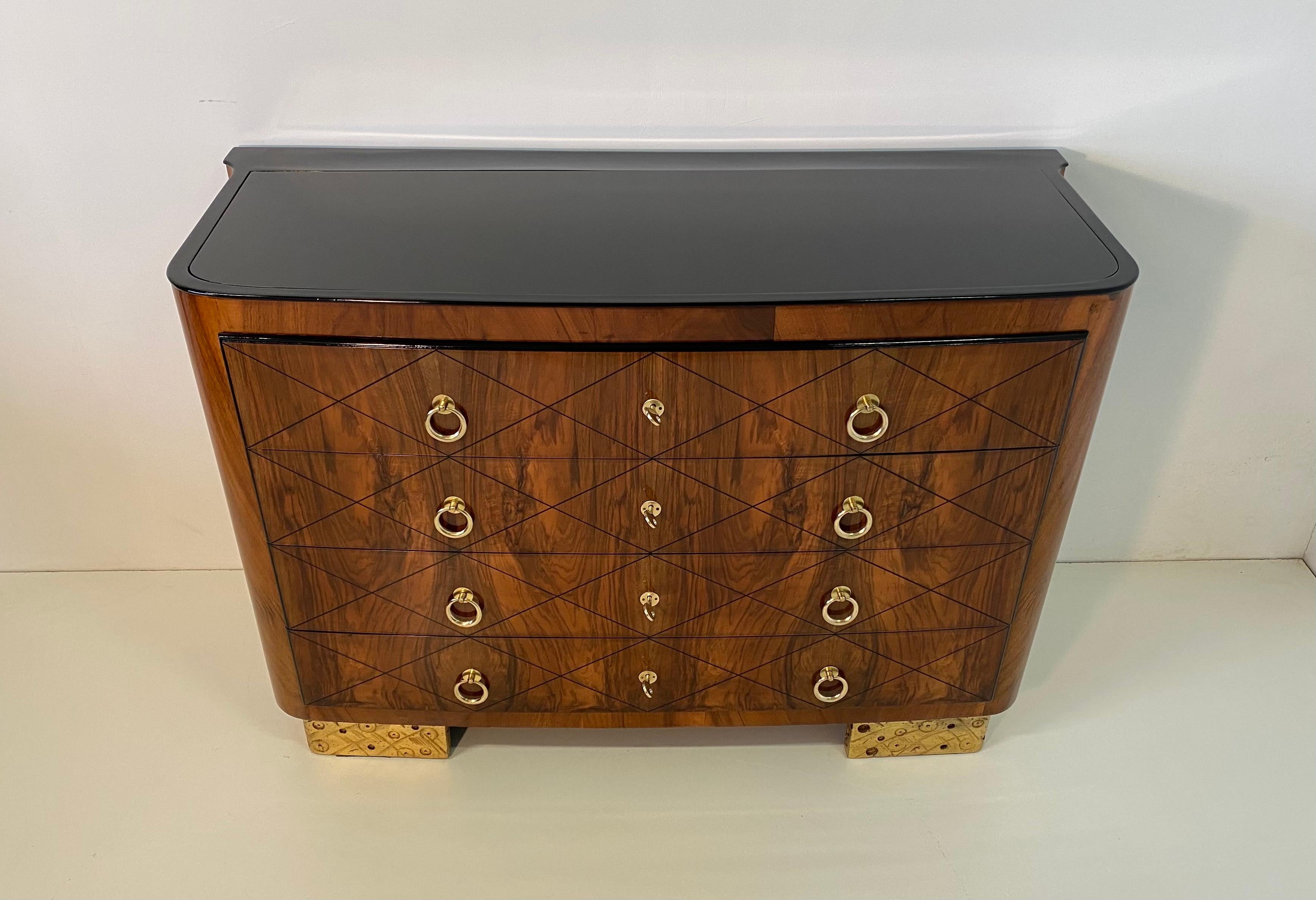 This chest of drawers was produced in Italy in the 1930s, it is completely covered in walnut briar while the top is in black glass with black lacquer details.
The front of the drawers is decorated with a Classic geometric pattern from the Art Deco