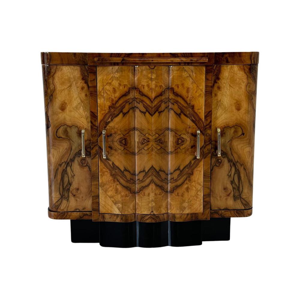 This elegant bar cabinet was produced in Italy in the 1930s. The piece of furniture has a particular, typically and purely Art Deco design and is completely covered in walnut briar with the exception of the base which is black lacquered. The gem of